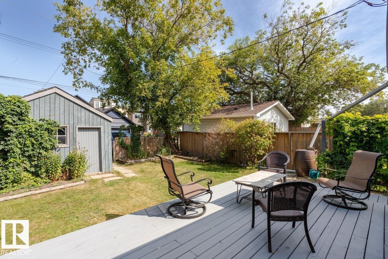 This property features a spacious yard with a well-maintained lawn and mature trees, offering a serene outdoor environment - 8736 76 Avenue, Edmonton, AB - Outdoor With Deck Patio Veranda