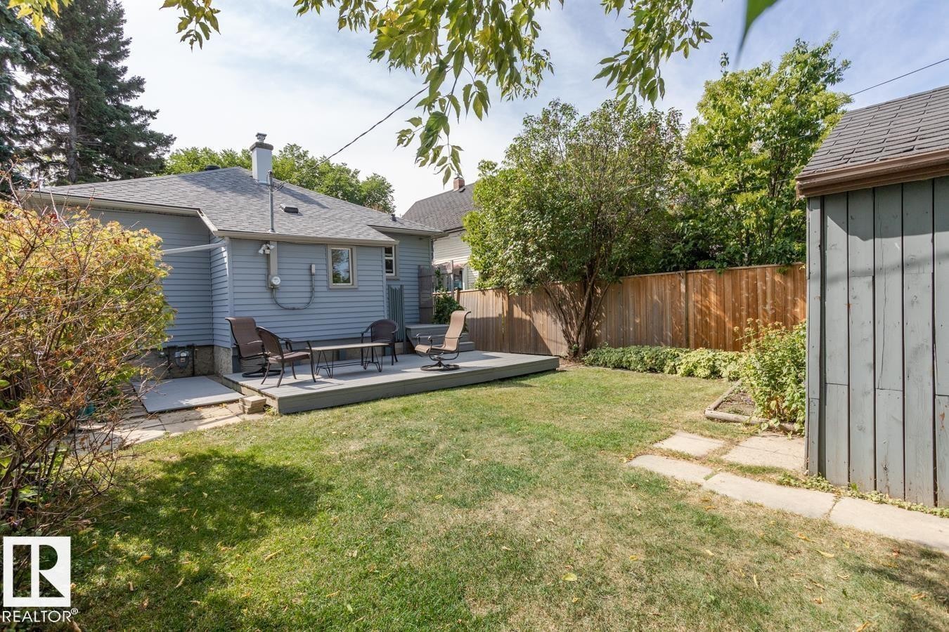 The property features a spacious backyard with a lawn, a wooden deck, and a shed - 8736 76 Avenue, Edmonton, AB - Outdoor With Deck Patio Veranda