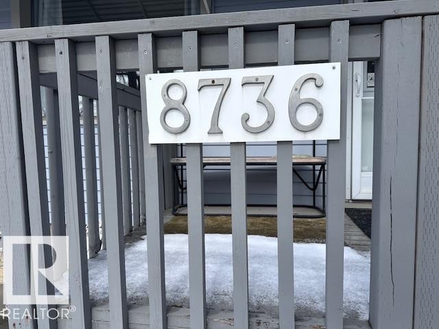 The property features a porch with gray wooden railings and a clearly visible house number display - 8736 76 Avenue, Edmonton, AB -