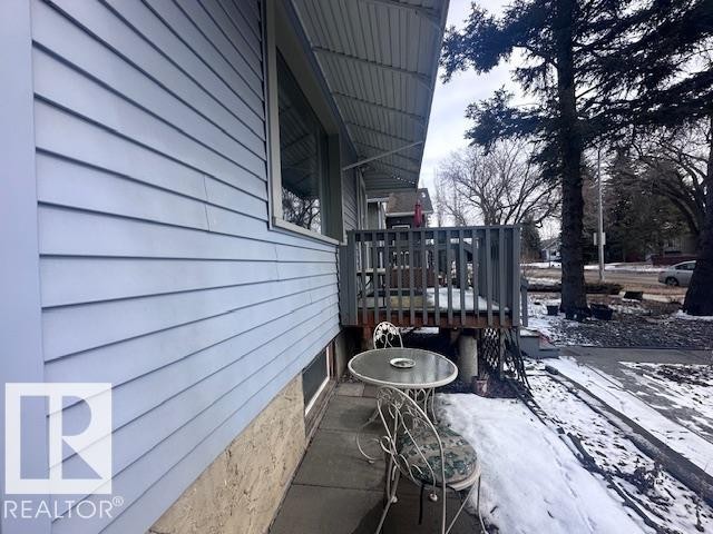 The property features light blue horizontal siding, a wooden deck with a gray railing, and a window with white trim - 8736 76 Avenue, Edmonton, AB - Outdoor
