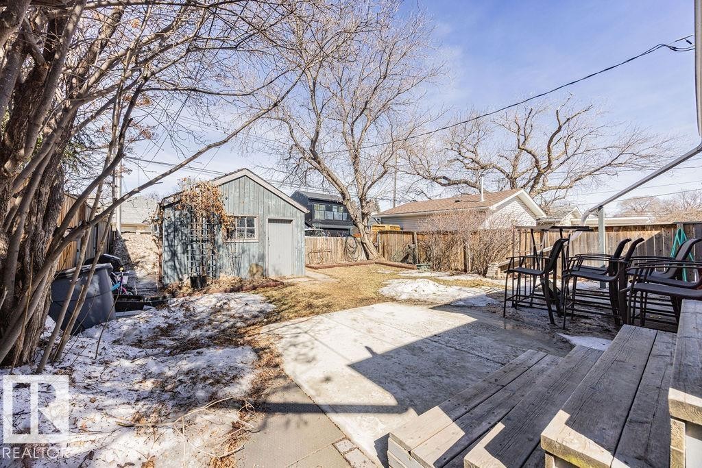 The property features a spacious yard with a shed, a wooden fence, and mature trees - 8736 76 Avenue, Edmonton, AB - Outdoor