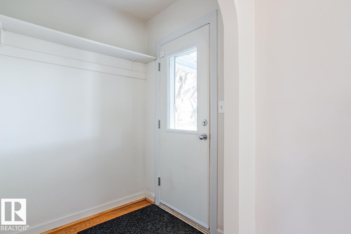Entryway featuring a white door with a window, hardwood flooring, and a storage shelf - 8736 76 Avenue, Edmonton, AB - Indoor Photo Showing Other Room
