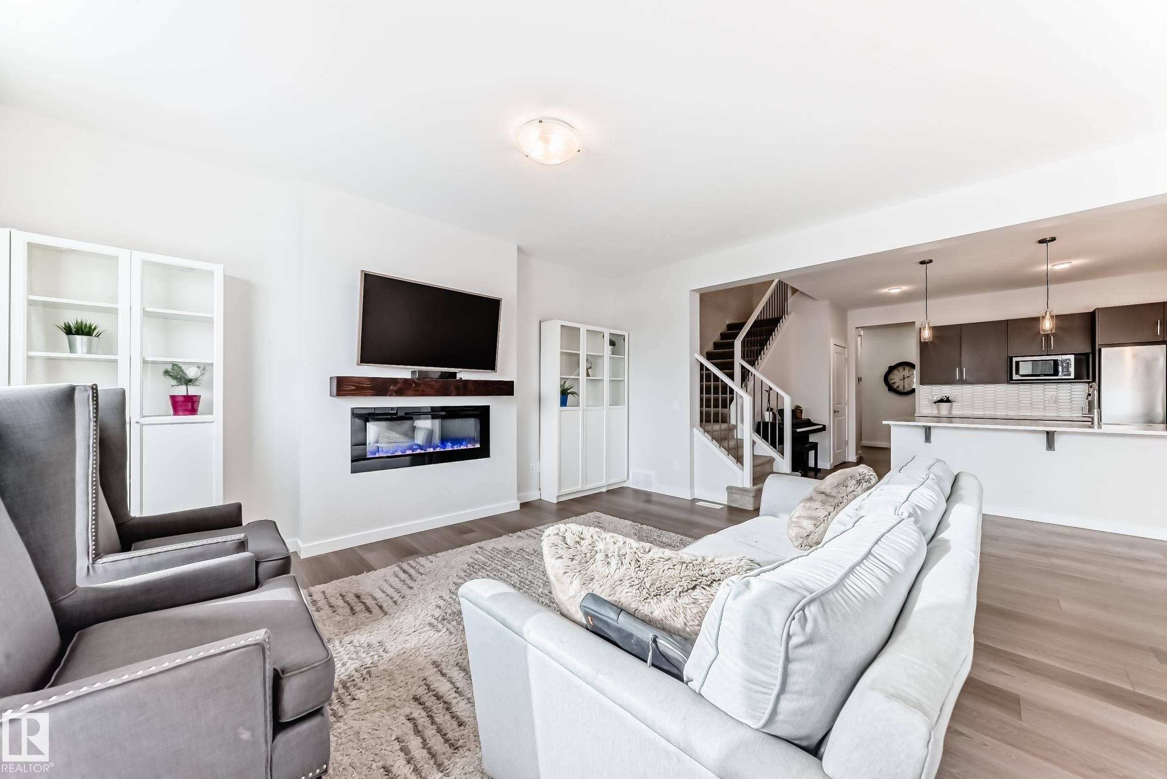 This living area features light hardwood flooring, an electric fireplace with a floating mantel, and ample natural light - 2935 Chokecherry Common, Edmonton, AB - Indoor Photo Showing Living Room With Fireplace