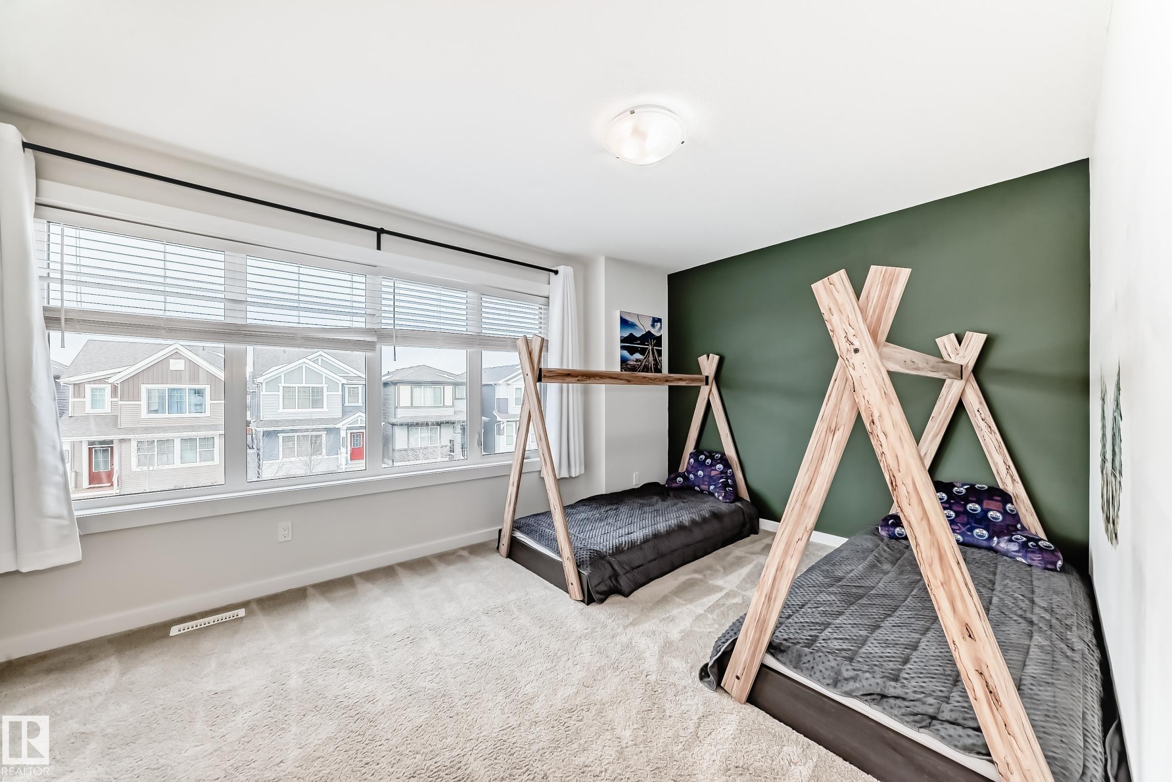 This room features a window with horizontal blinds, light-colored carpeting, a wall painted in a dark green hue, and a ceiling light fixture - 2935 Chokecherry Common, Edmonton, AB - Indoor