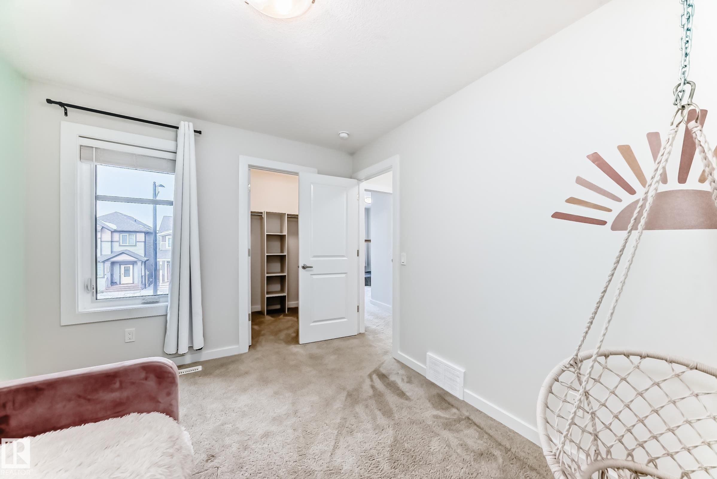 This room features light-colored carpeted flooring, a window providing natural light, and a closet with shelving - 2935 Chokecherry Common, Edmonton, AB - Indoor Photo Showing Other Room