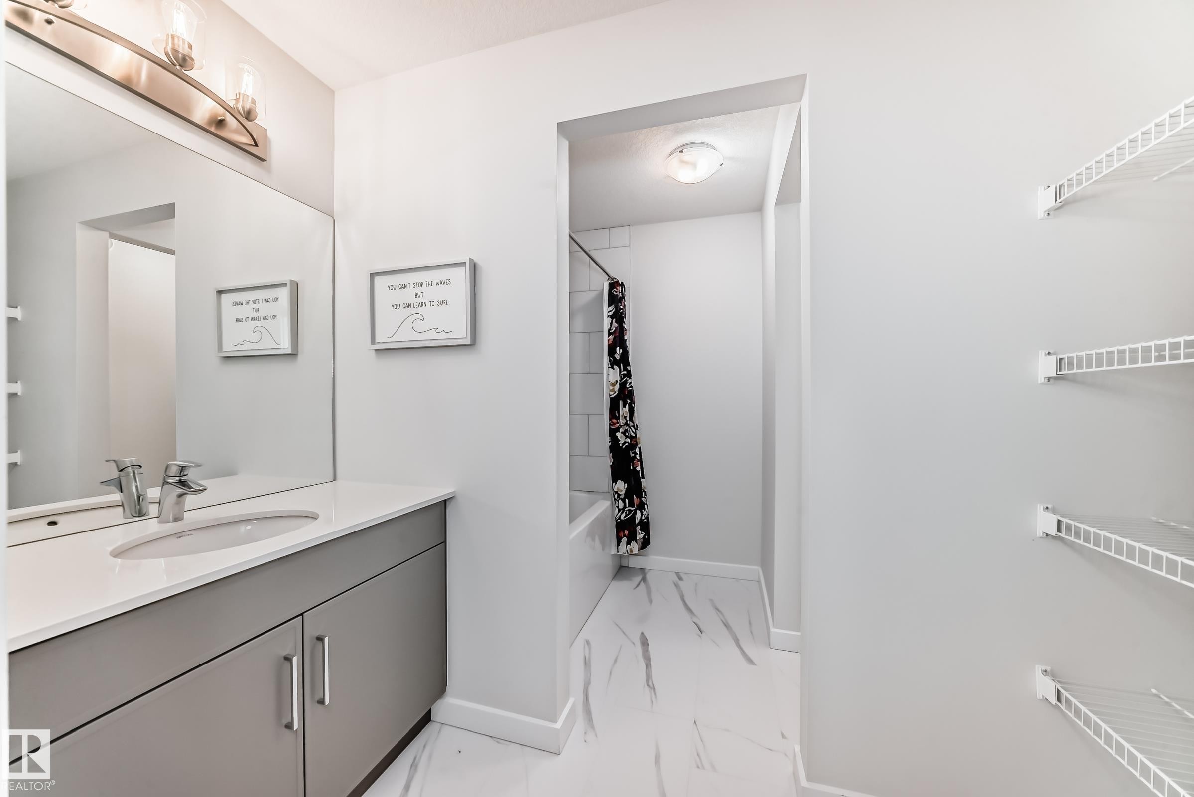 Well-appointed bathroom featuring a vanity with a white countertop, an undermount sink, and a large mirror with overhead lighting - 2935 Chokecherry Common, Edmonton, AB - Indoor