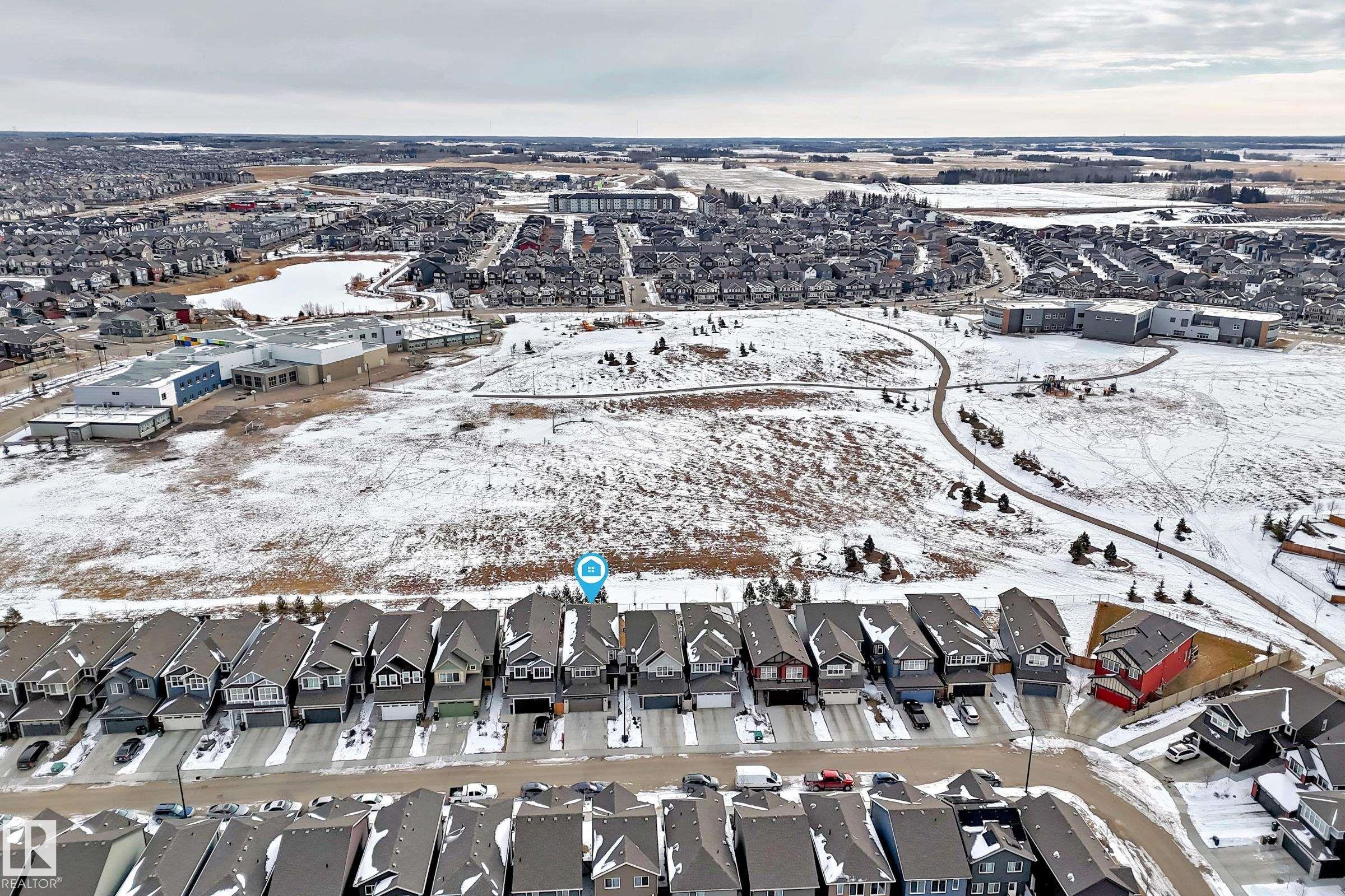 Aerial view of the property and its surrounding neighbourhood, featuring nearby properties, a paved path, and a body of water - 2935 Chokecherry Common, Edmonton, AB - Outdoor With View