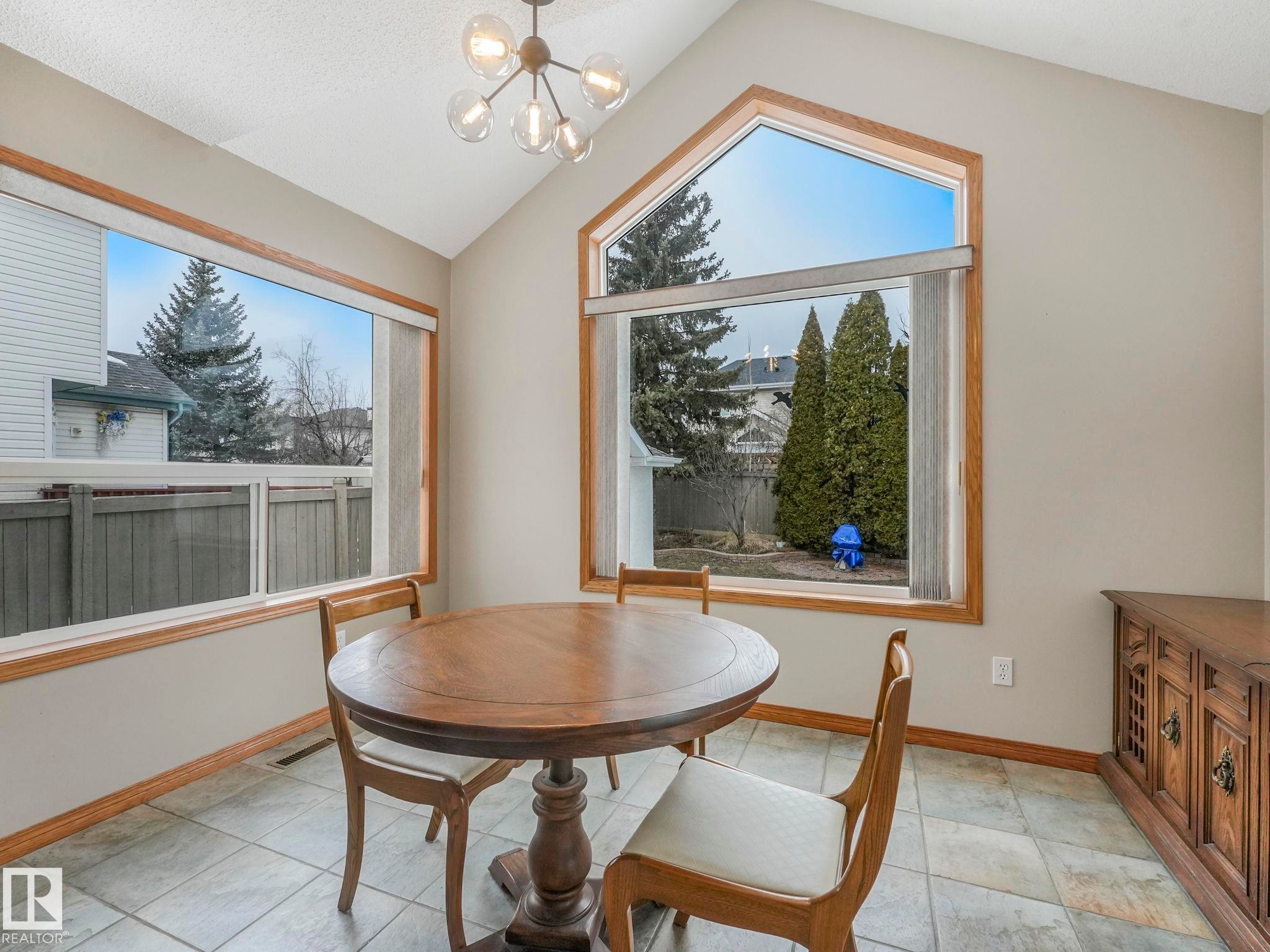 This room features a vaulted ceiling, large windows with wood trim, and tile flooring - 11704 11 Avenue, Edmonton, AB - Indoor Photo Showing Dining Room