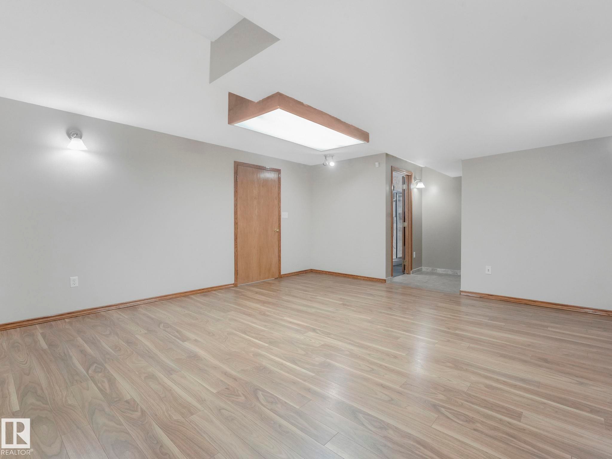Spacious room featuring light-colored walls, light wood-look flooring, and a ceiling-mounted light fixture - 11704 11 Avenue, Edmonton, AB - Indoor Photo Showing Other Room