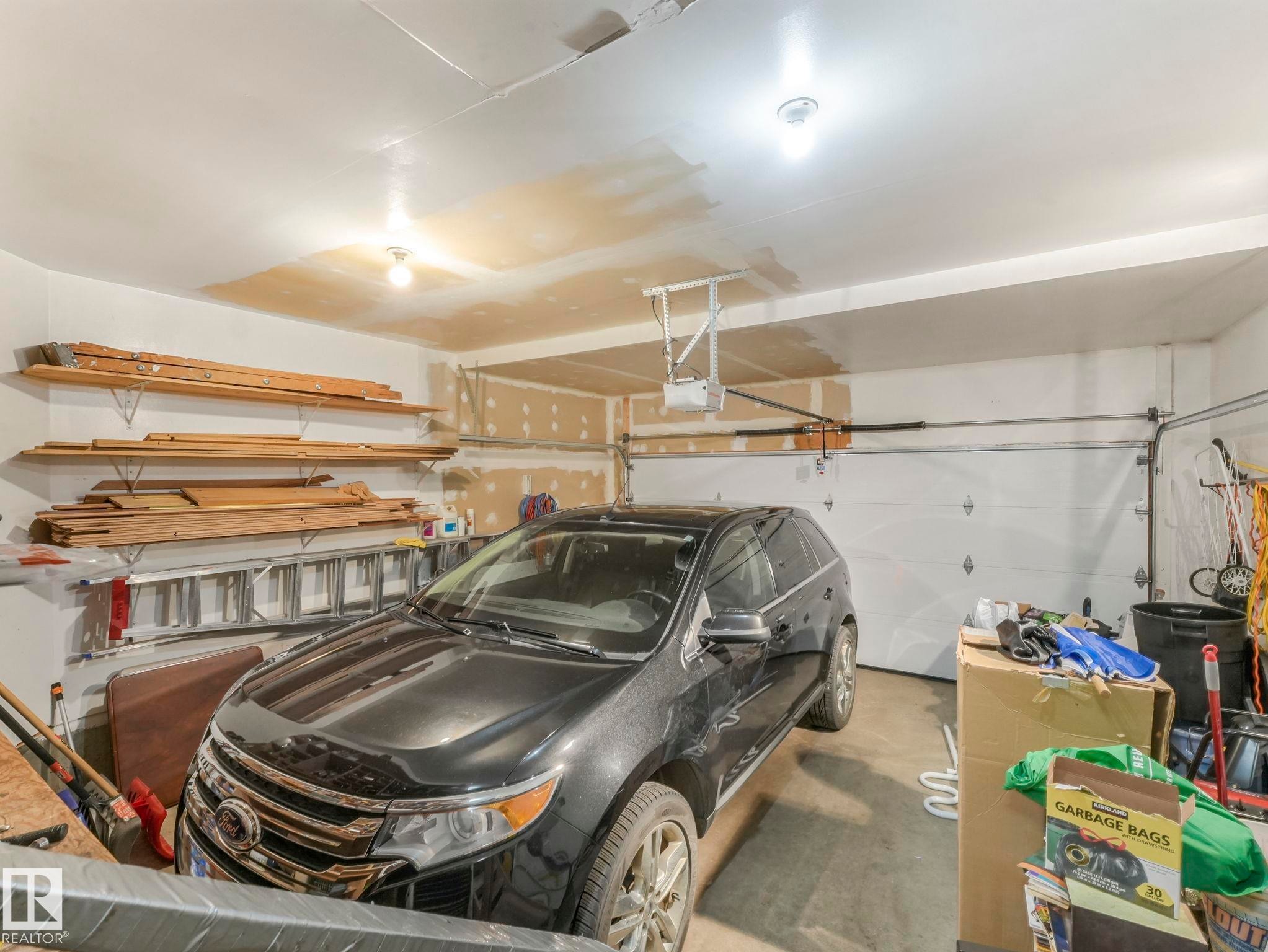 The property includes a spacious garage with a white overhead door and overhead lighting - 11704 11 Avenue, Edmonton, AB - Indoor Photo Showing Garage