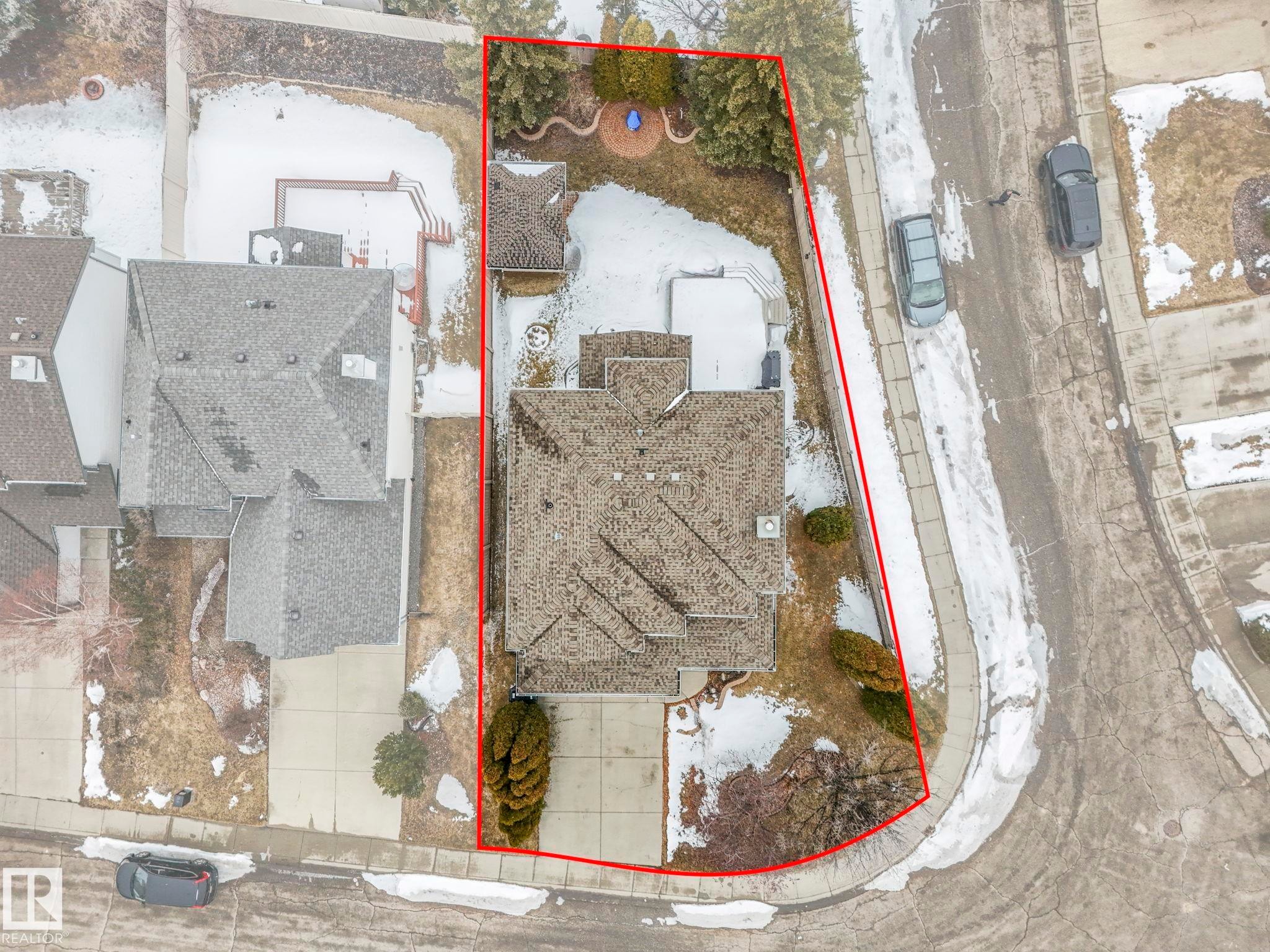Aerial view of the property, showcasing its extensive lot with a driveway, a sloped yard, and a patio area - 11704 11 Avenue, Edmonton, AB -