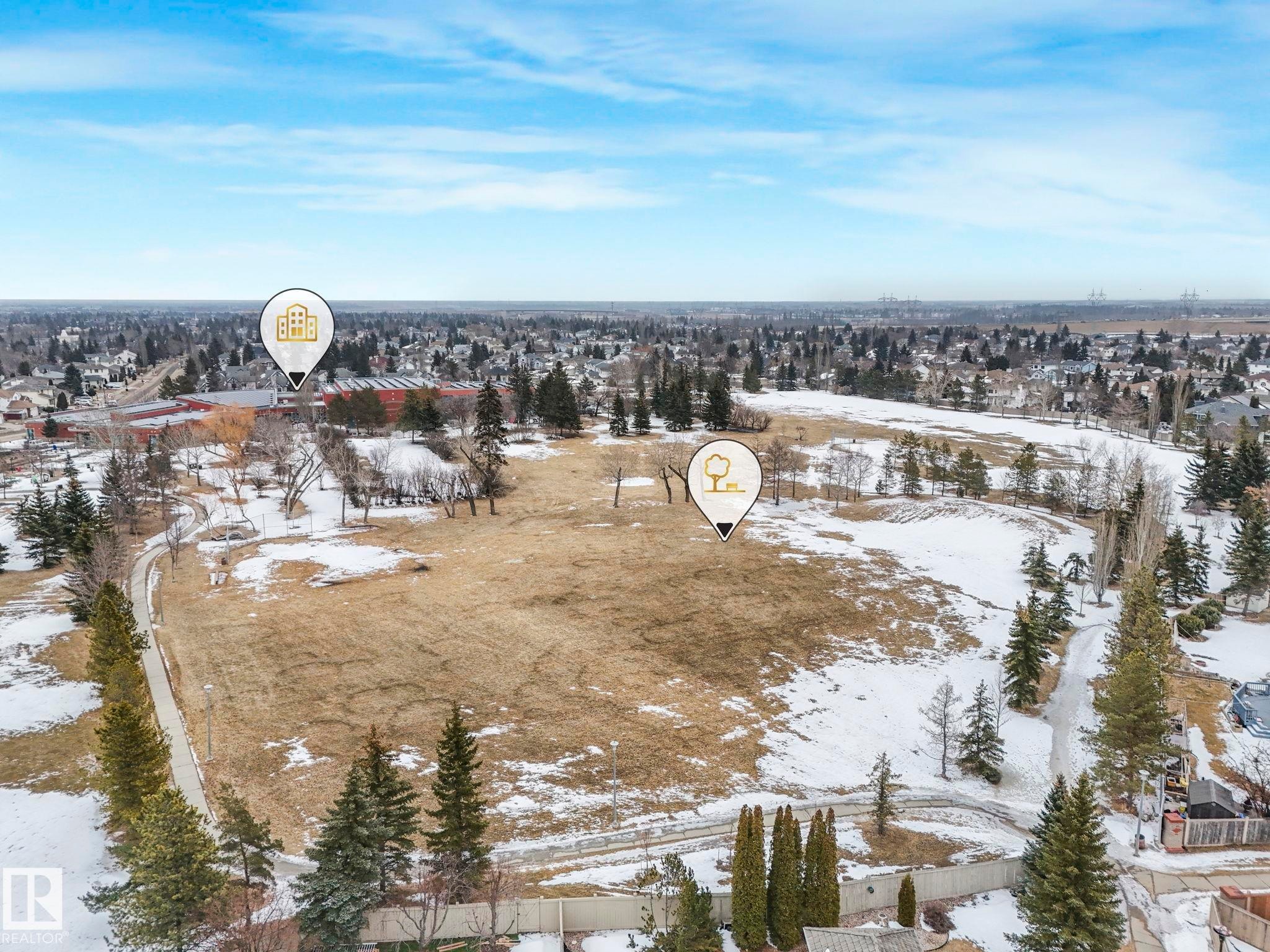 Aerial view showcasing the expansive grounds, partially covered with snow, and bordered by mature evergreen trees - 11704 11 Avenue, Edmonton, AB - Outdoor With View