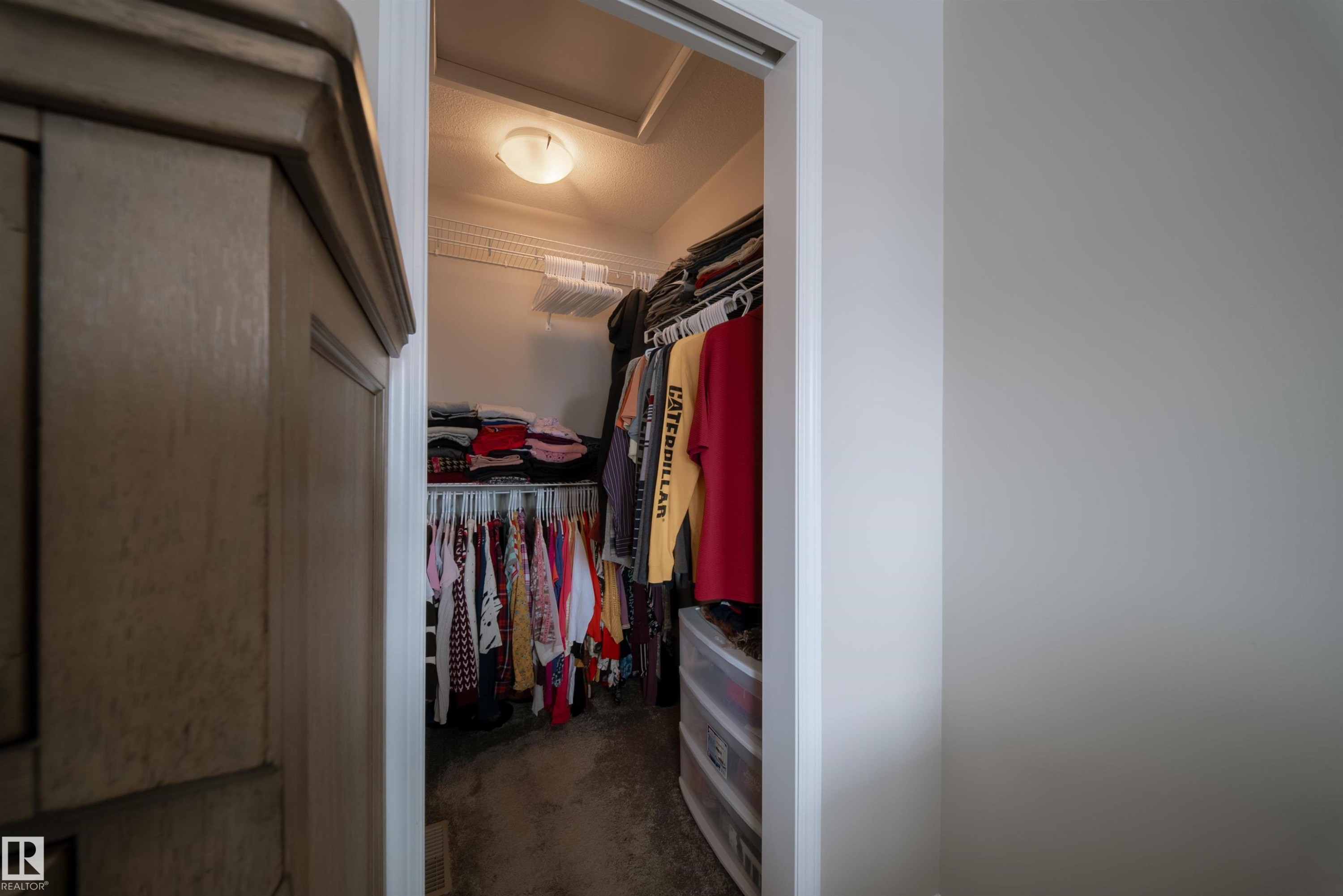 The property includes a closet with built-in shelving and hanging rods, illuminated by an overhead light fixture - 2132 52 St, Edmonton, AB - Indoor Photo Showing Other Room