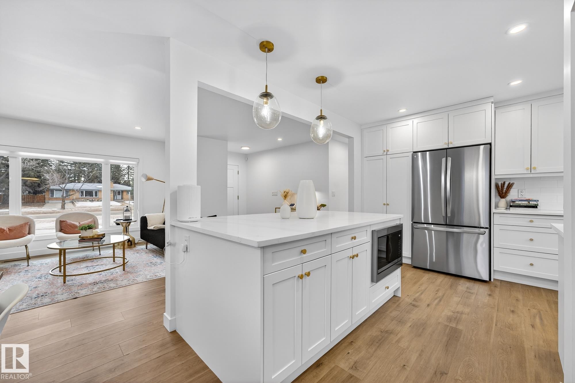 Kitchen with freestanding refrigerator, white cabinetry, black microwave, a kitchen island, and light wood-style flooring - 8604 142 Street, Edmonton, AB - Indoor Photo Showing Kitchen With Stainless Steel Kitchen With Upgraded Kitchen