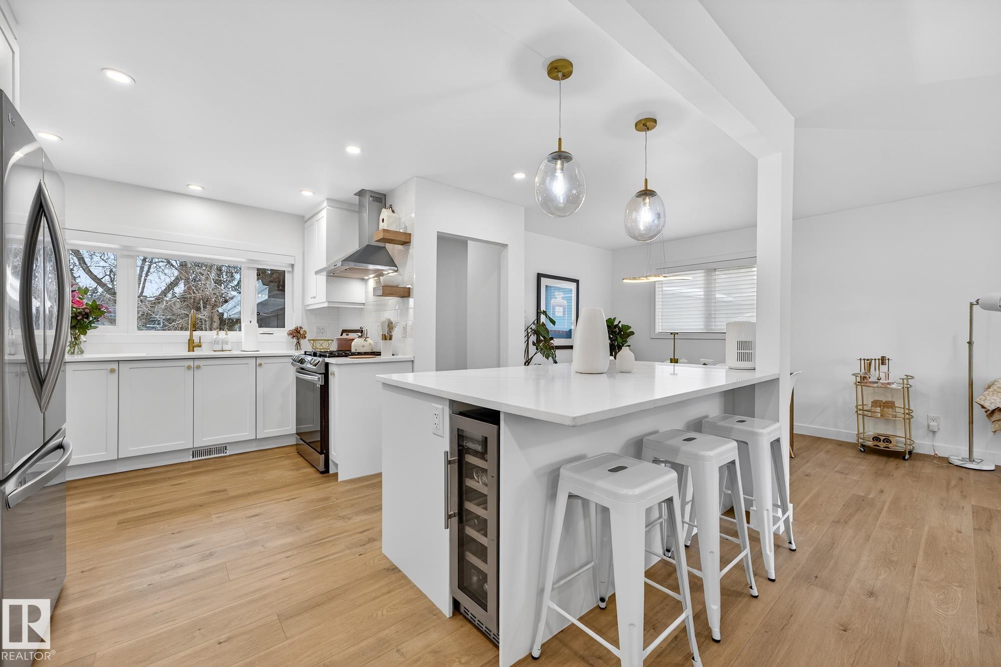 Kitchen featuring a breakfast bar, white cabinets, freestanding refrigerator, decorative light fixtures, and light wood-style floors - 8604 142 Street, Edmonton, AB - Indoor Photo Showing Kitchen With Upgraded Kitchen
