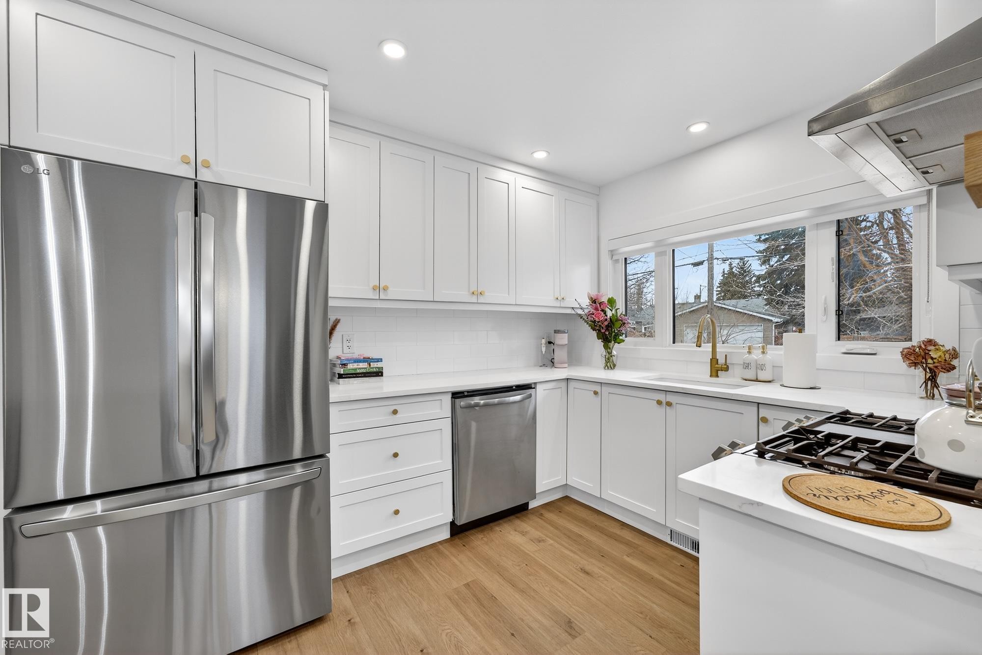 Kitchen with stainless steel appliances, exhaust hood, white cabinets, light wood finished floors, and recessed lighting - 8604 142 Street, Edmonton, AB - Indoor Photo Showing Kitchen With Stainless Steel Kitchen With Upgraded Kitchen