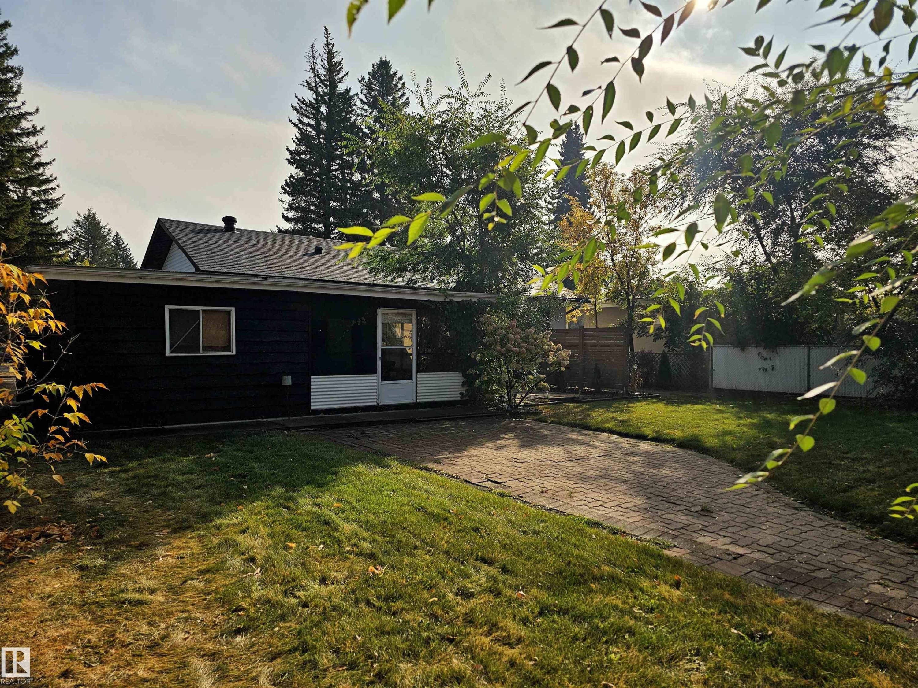 The property features a dark-colored exterior with a white trim, a sloped roof, and a visible window - 8604 142 Street, Edmonton, AB - Outdoor