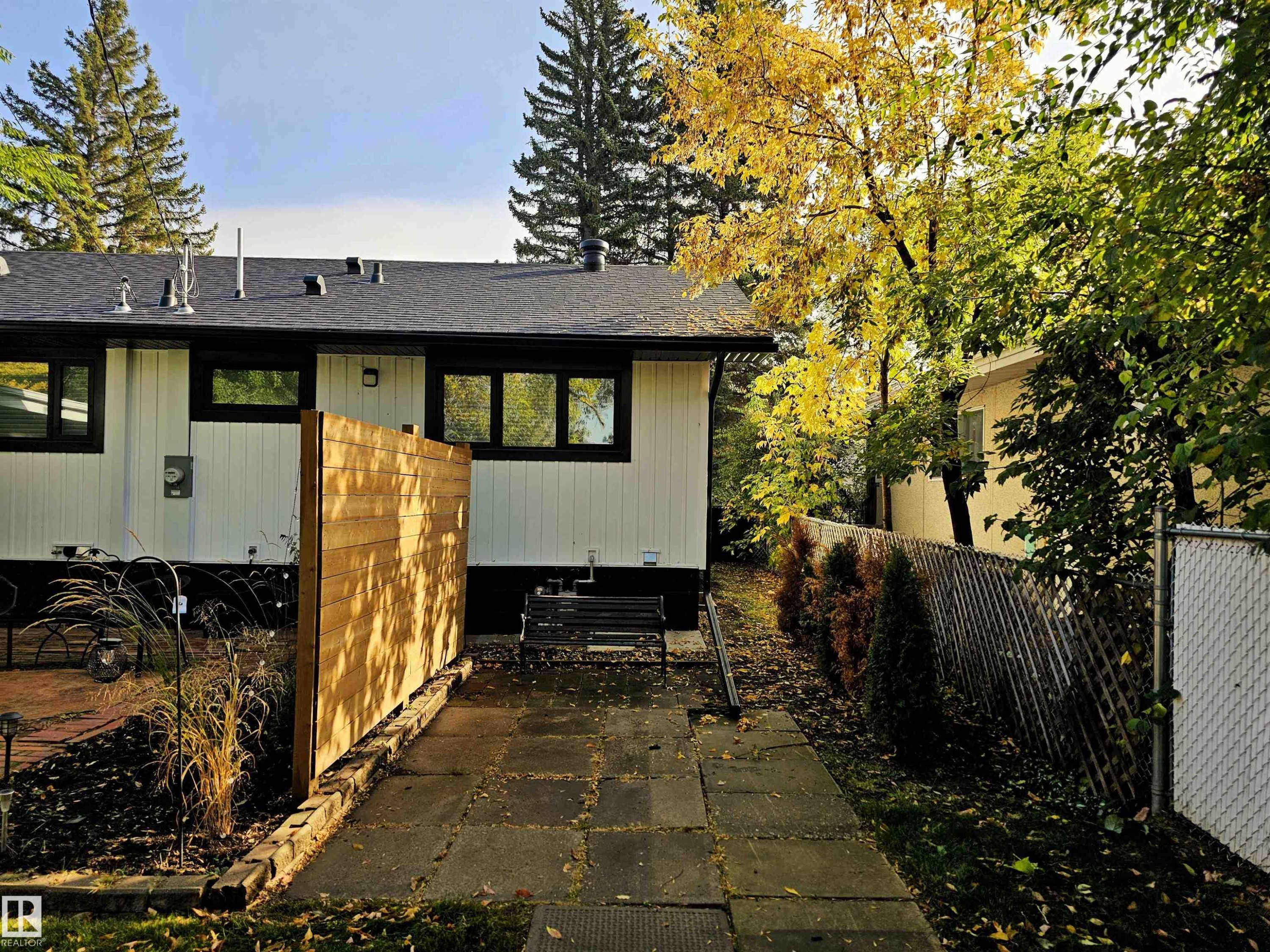 The property features a white exterior with black trim, a dark roof, and a paved walkway - 8604 142 Street, Edmonton, AB - Outdoor
