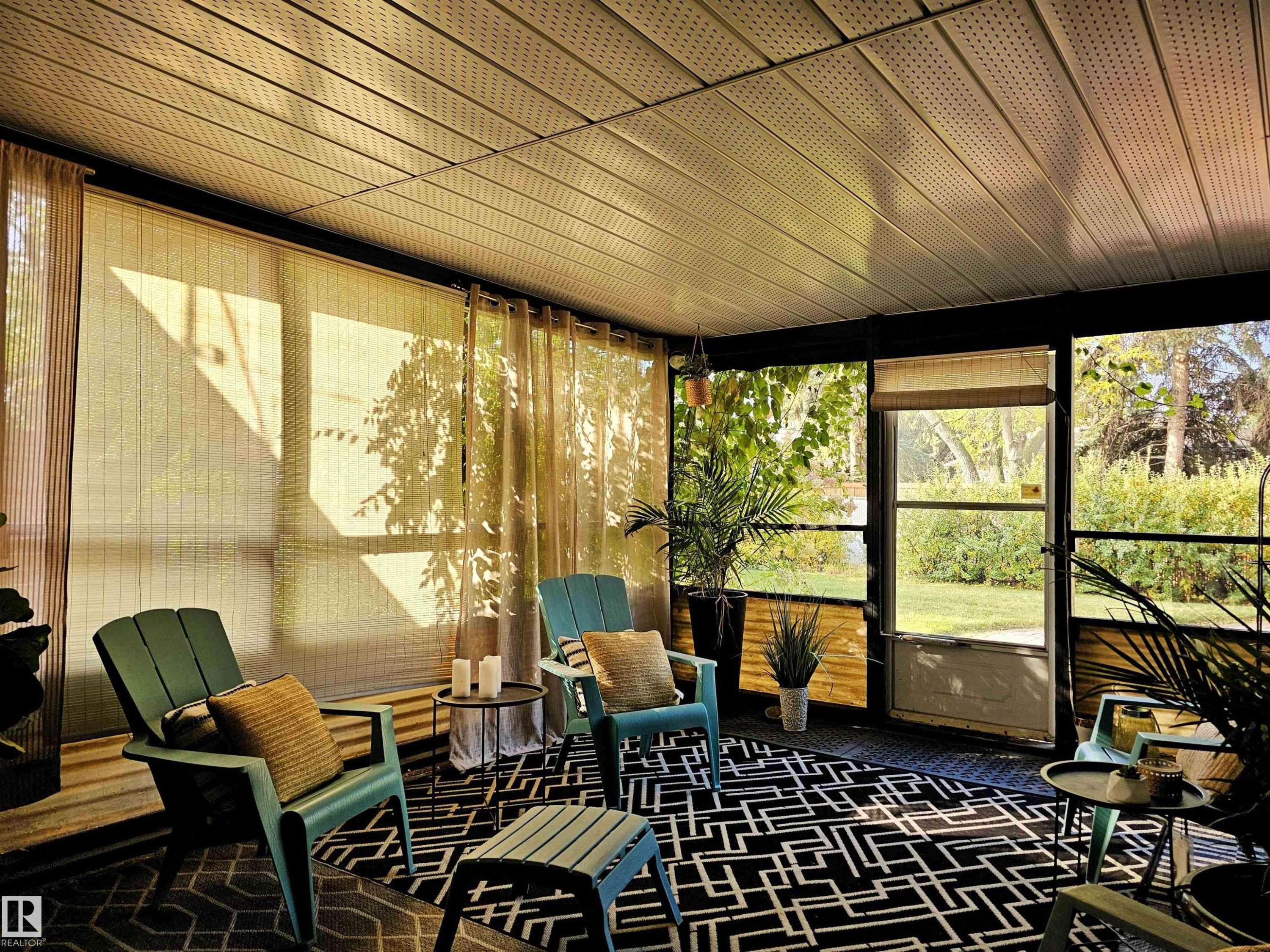 Enclosed patio space with a screened door and windows, featuring a geometric patterned rug and a paneled ceiling - 8604 142 Street, Edmonton, AB - With Exterior