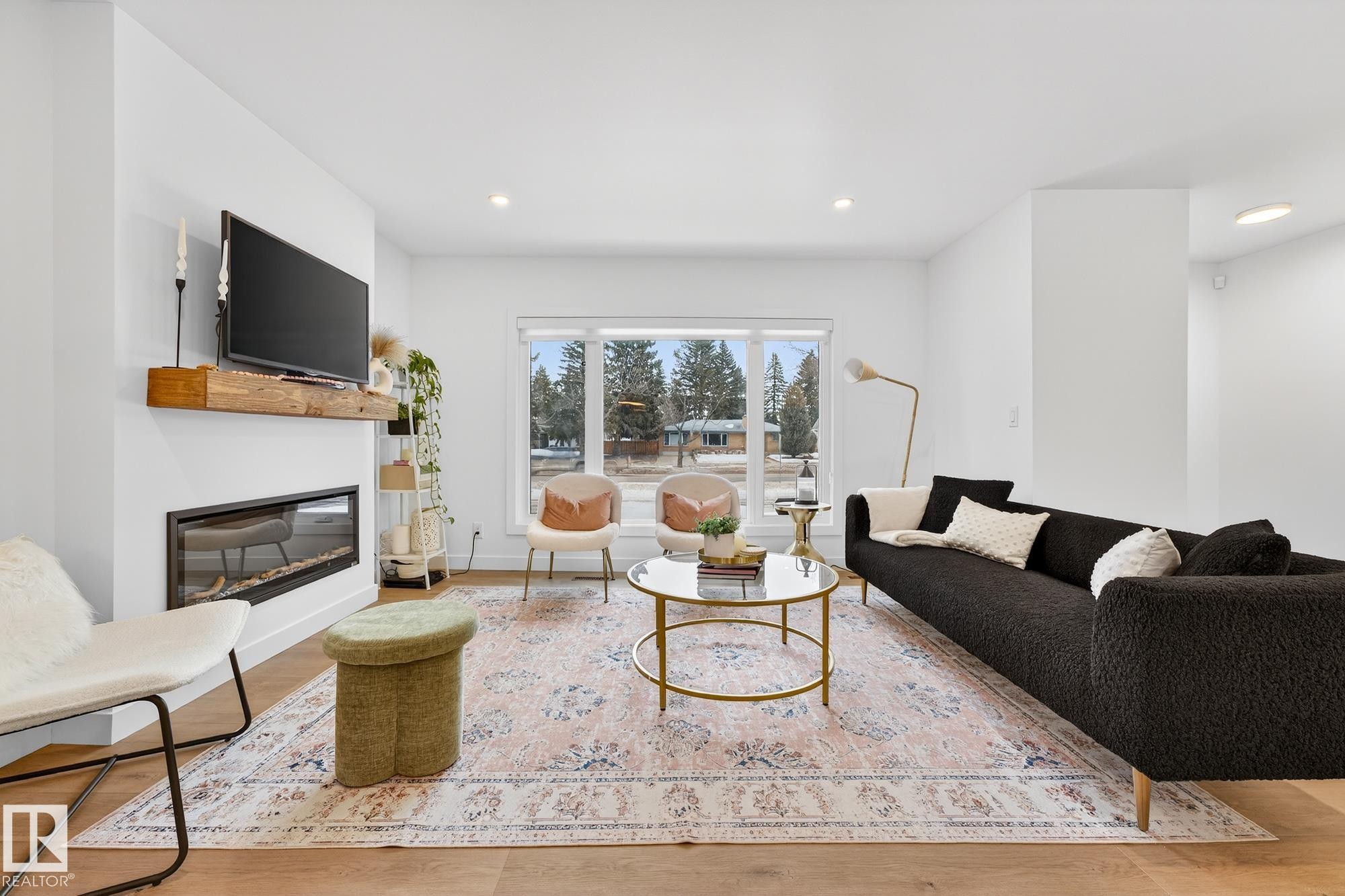 Living area featuring light wood-style flooring, a glass covered fireplace, and recessed lighting - 8604 142 Street, Edmonton, AB - Indoor Photo Showing Living Room With Fireplace