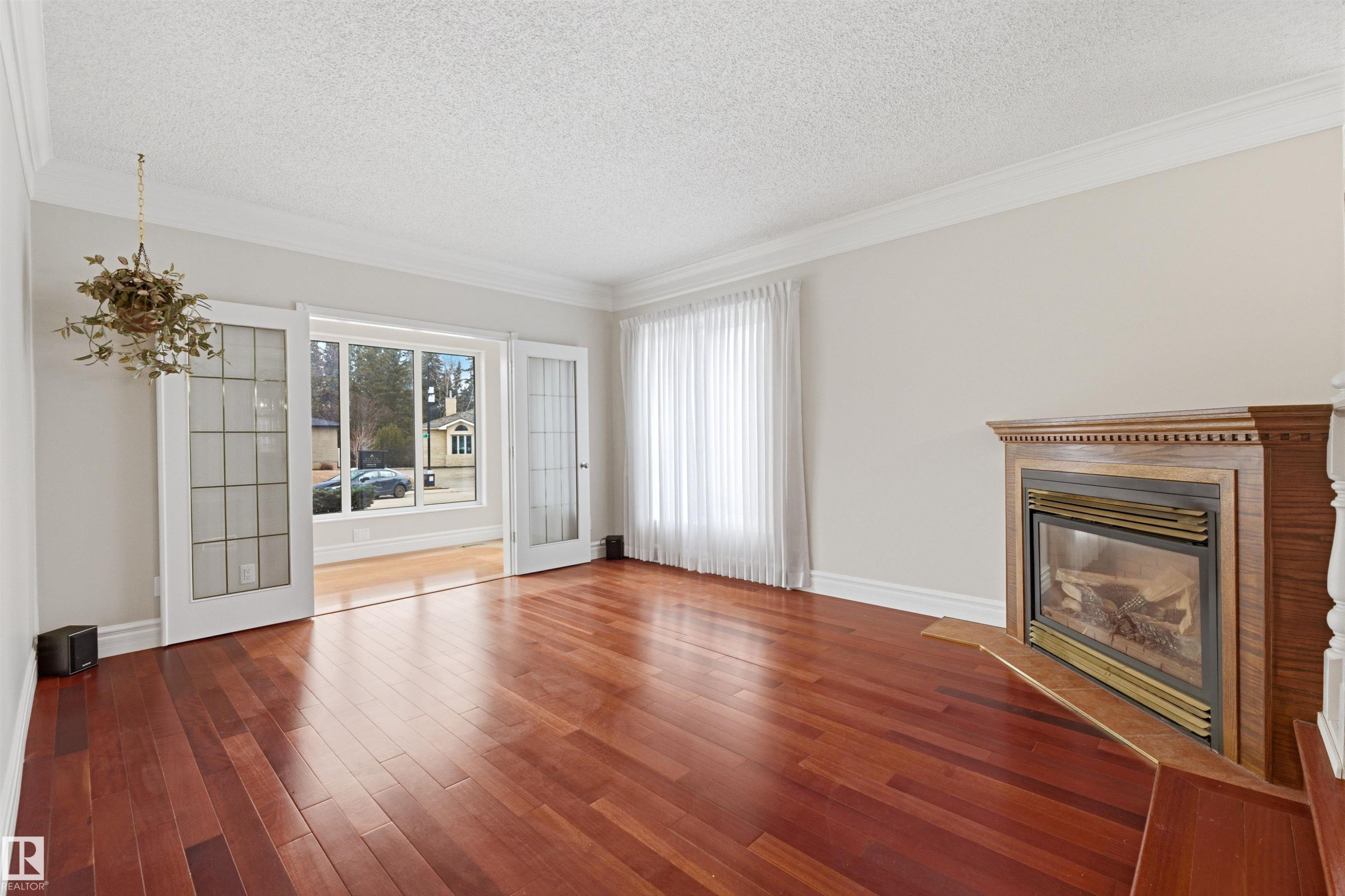 This inviting living space features rich hardwood flooring, a classic wooden fireplace with a hearth, and elegant crown molding - 131 Walsh Crescent, Edmonton, AB - Indoor Photo Showing Living Room With Fireplace