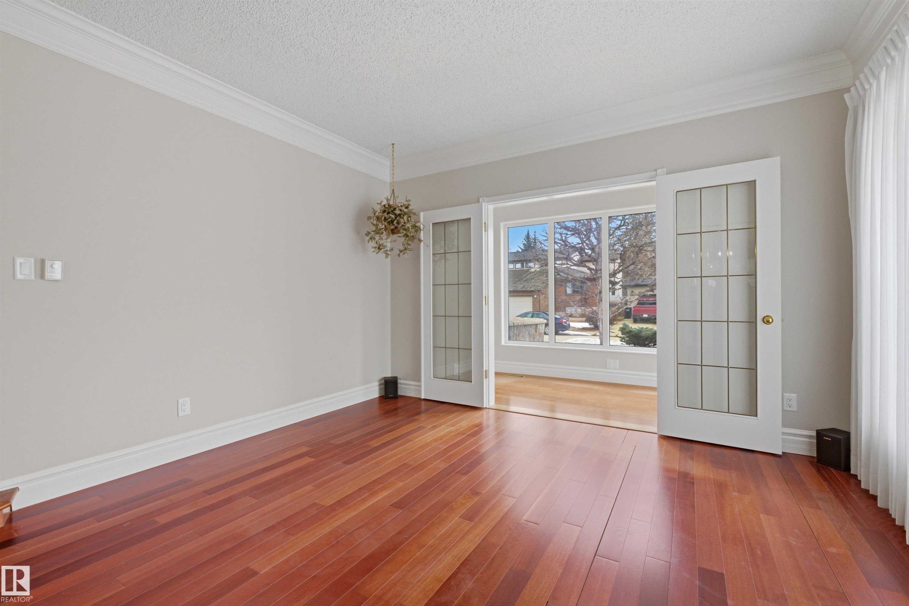 This room features rich hardwood flooring, light-colored walls, white baseboards, and elegant crown molding - 131 Walsh Crescent, Edmonton, AB - Indoor Photo Showing Other Room