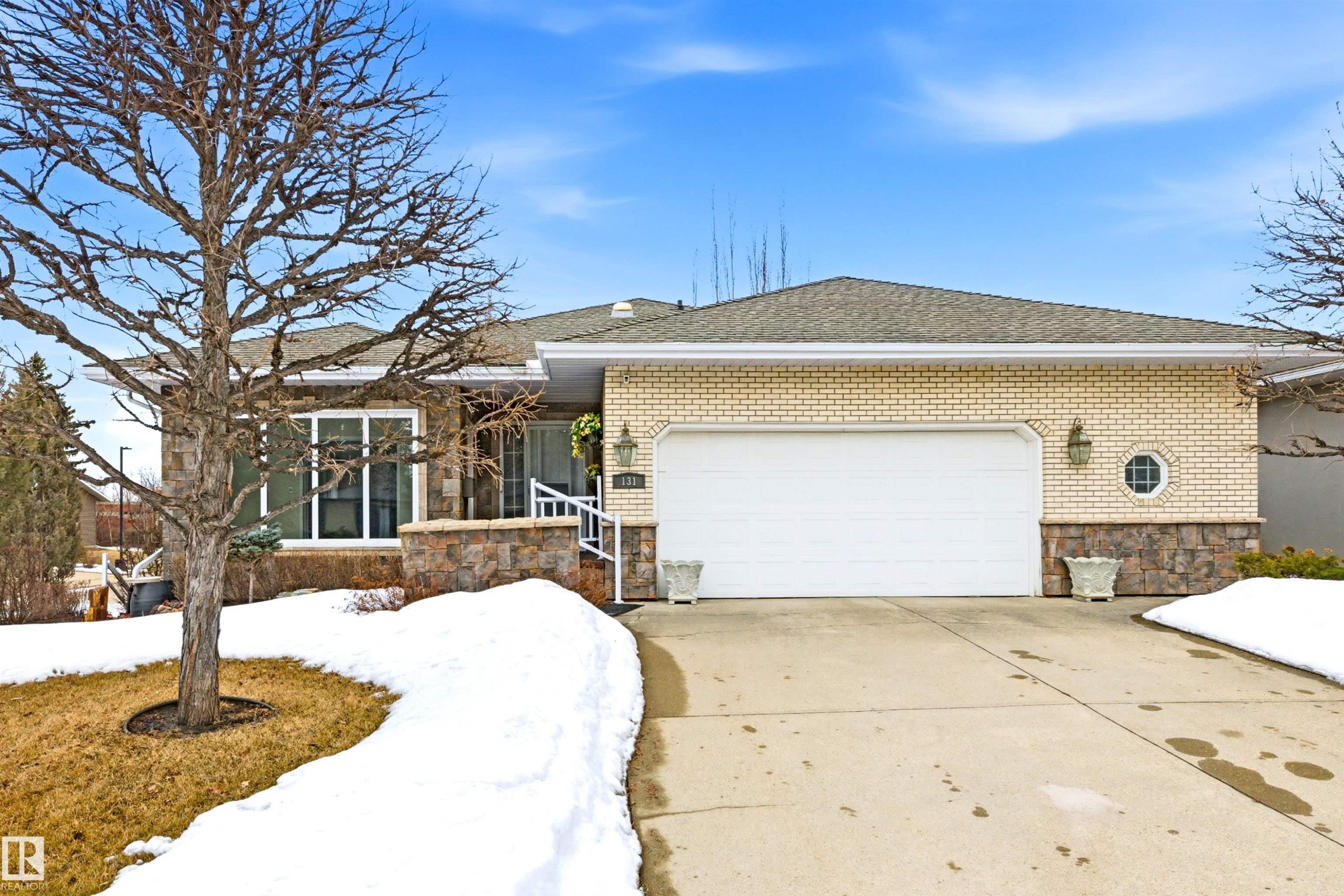 The property features a brick and stone exterior, a driveway, and an attached garage with a white door - 131 Walsh Crescent, Edmonton, AB - Outdoor
