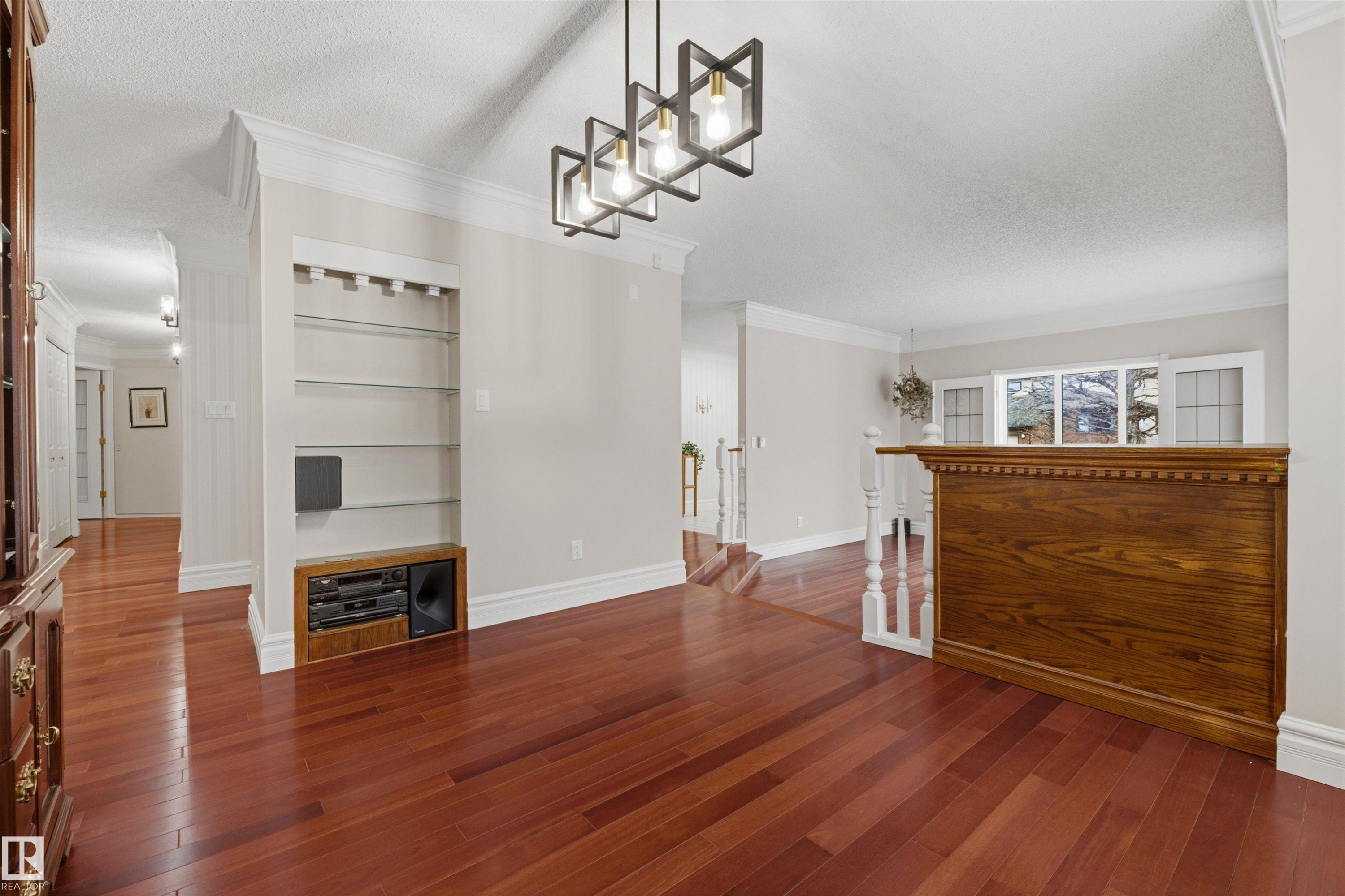 This inviting space features rich hardwood flooring, crown molding, and a contemporary chandelier - 131 Walsh Crescent, Edmonton, AB - Indoor Photo Showing Other Room