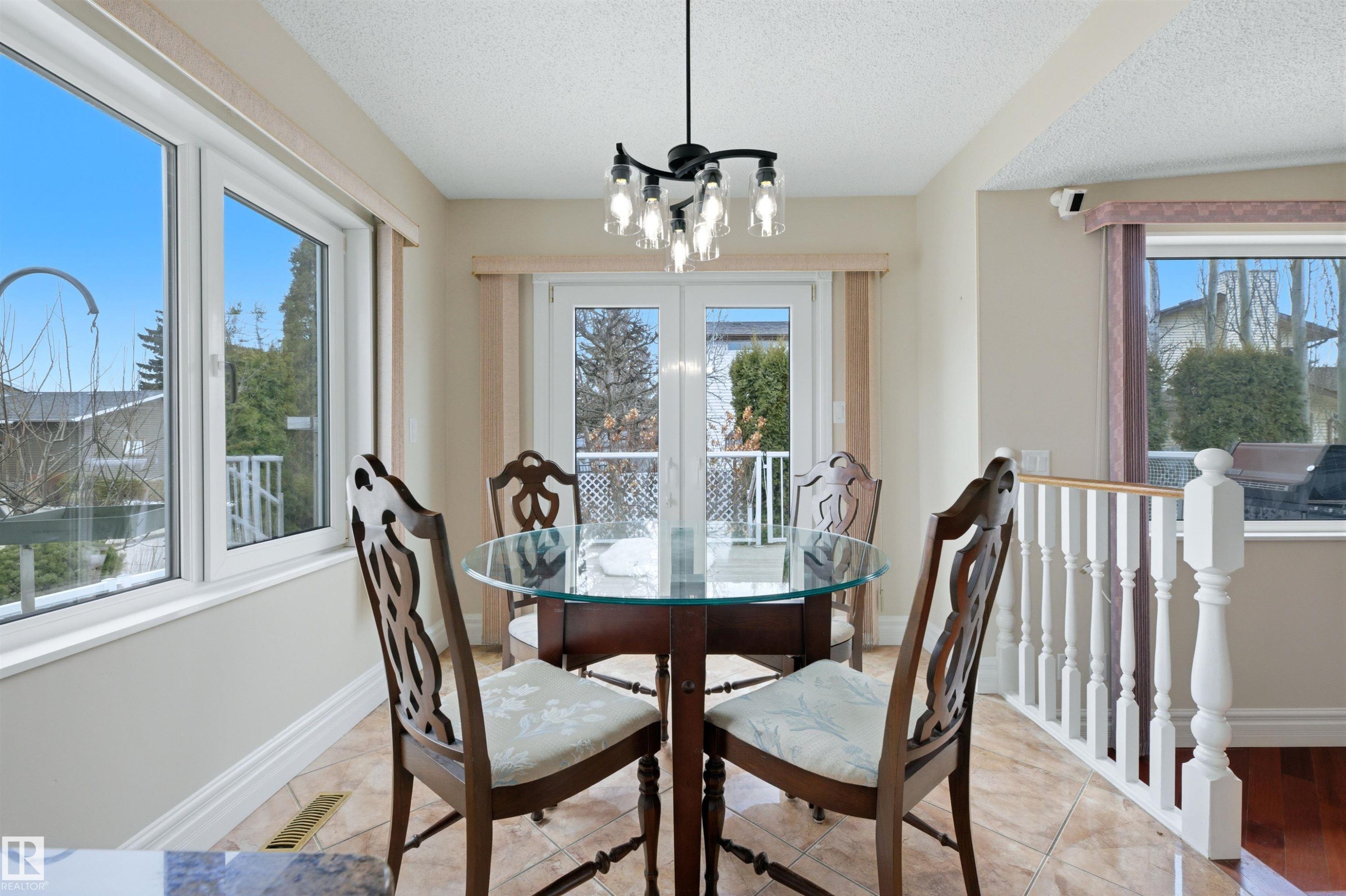 Dining area featuring tile flooring, a glass-top table, and a white balustrade - 131 Walsh Crescent, Edmonton, AB - Indoor Photo Showing Dining Room