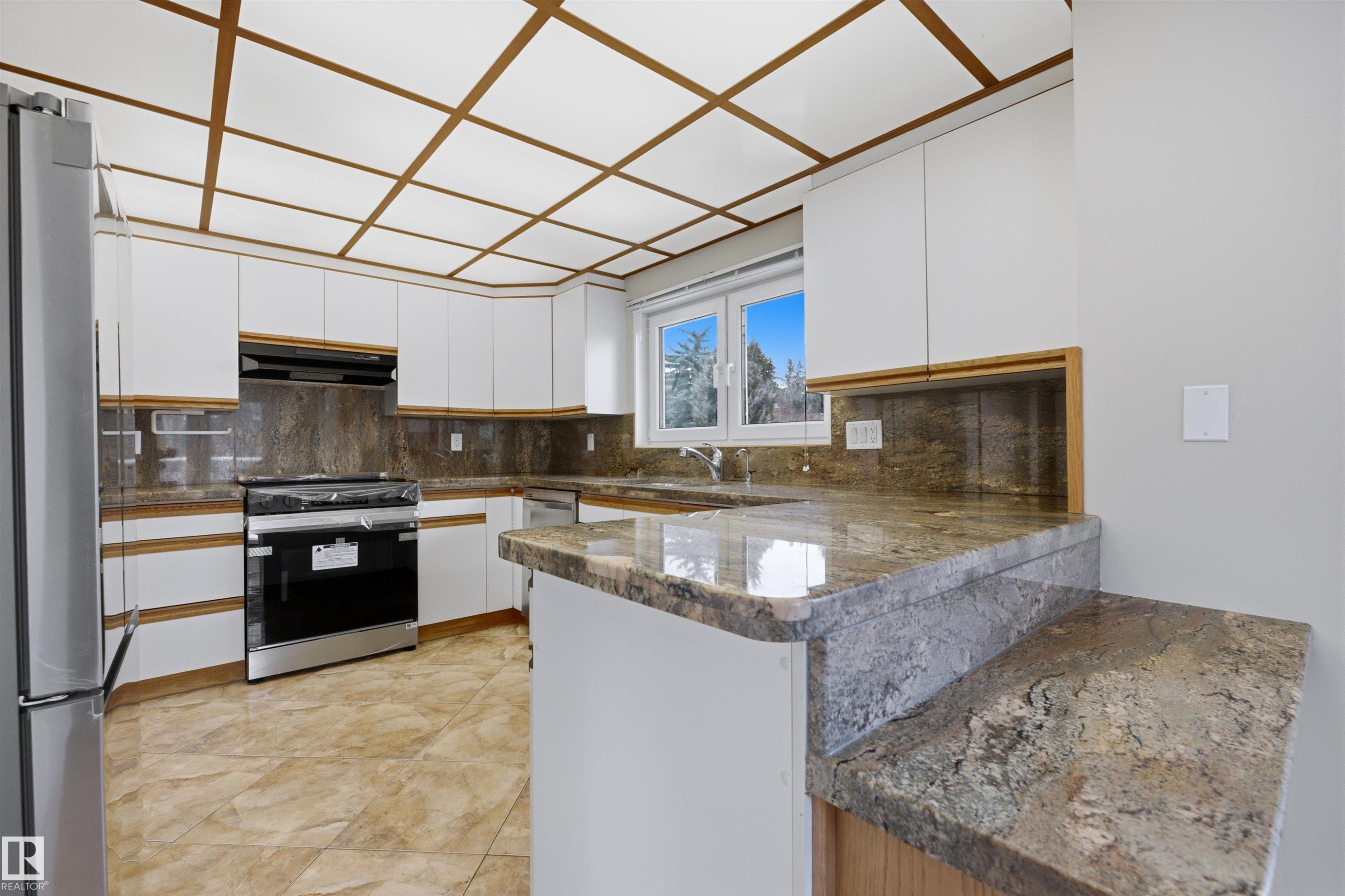 The kitchen features white cabinetry, granite countertops, tile flooring, and a stainless steel oven - 131 Walsh Crescent, Edmonton, AB - Indoor Photo Showing Kitchen