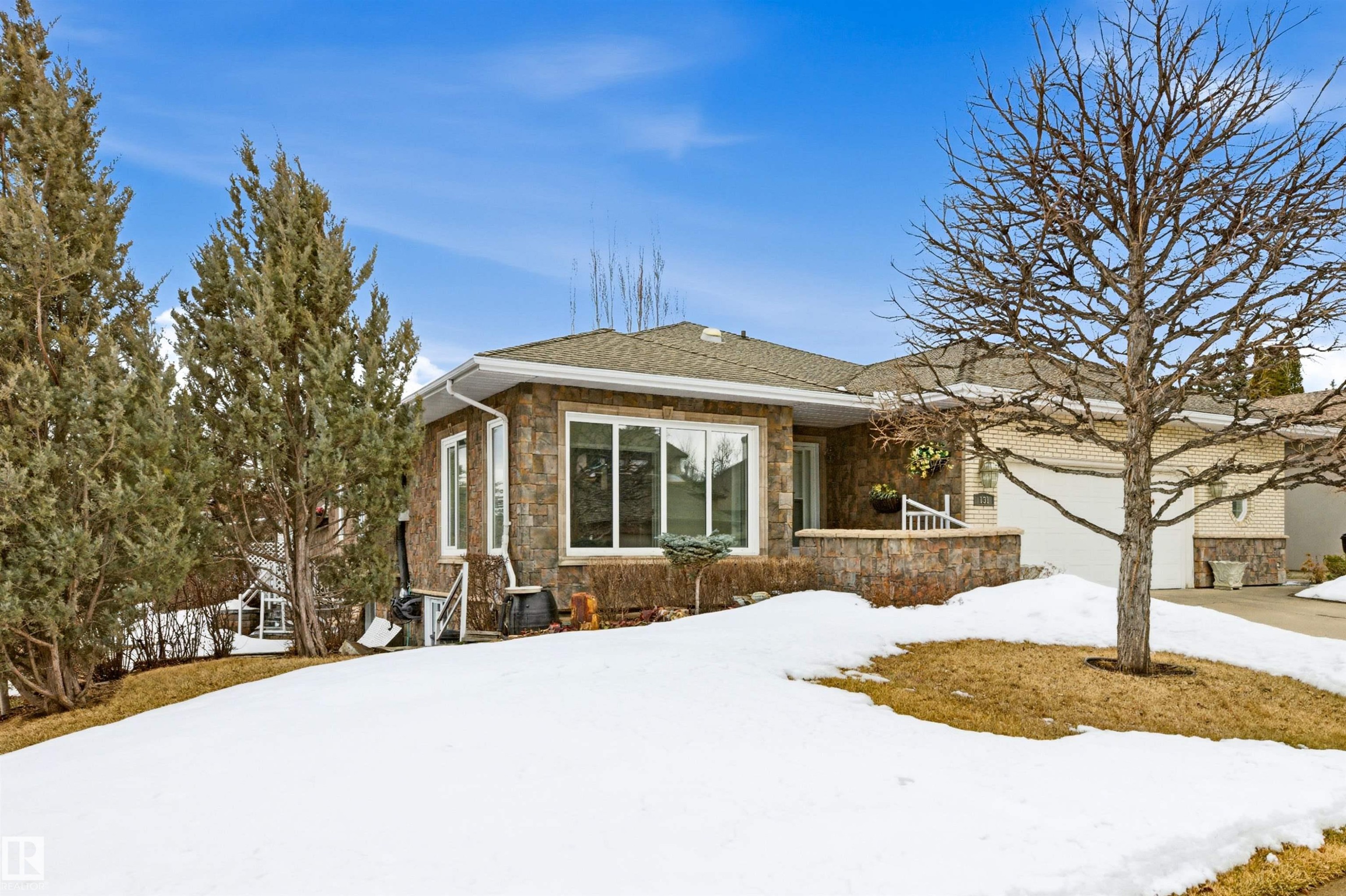 The property features a stone facade, a light-colored roof, and an attached garage - 131 Walsh Crescent, Edmonton, AB - Outdoor