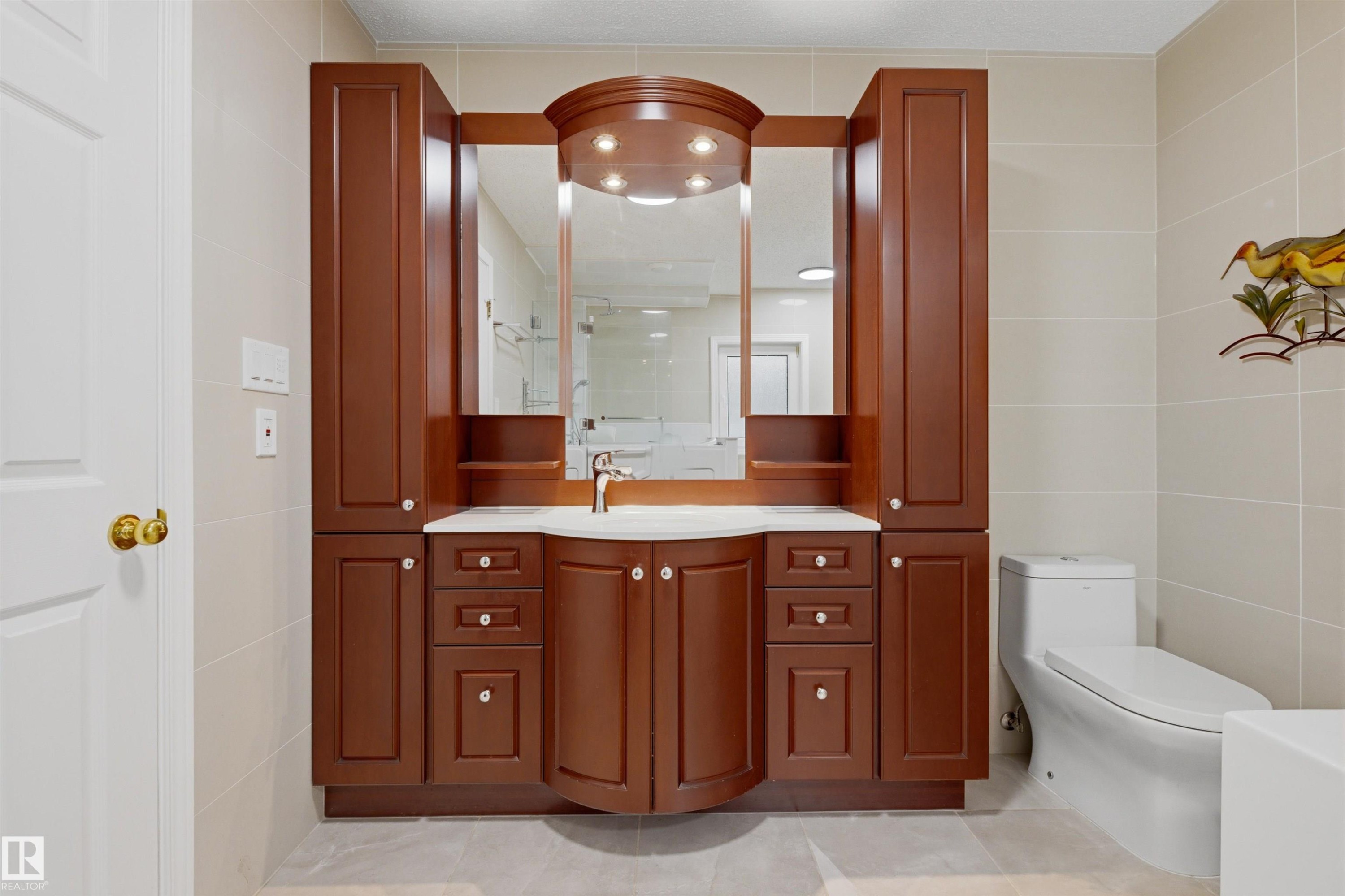 Bathroom featuring a wood vanity with a white countertop, an integrated sink, and an illuminated mirror - 131 Walsh Crescent, Edmonton, AB - Indoor Photo Showing Bathroom