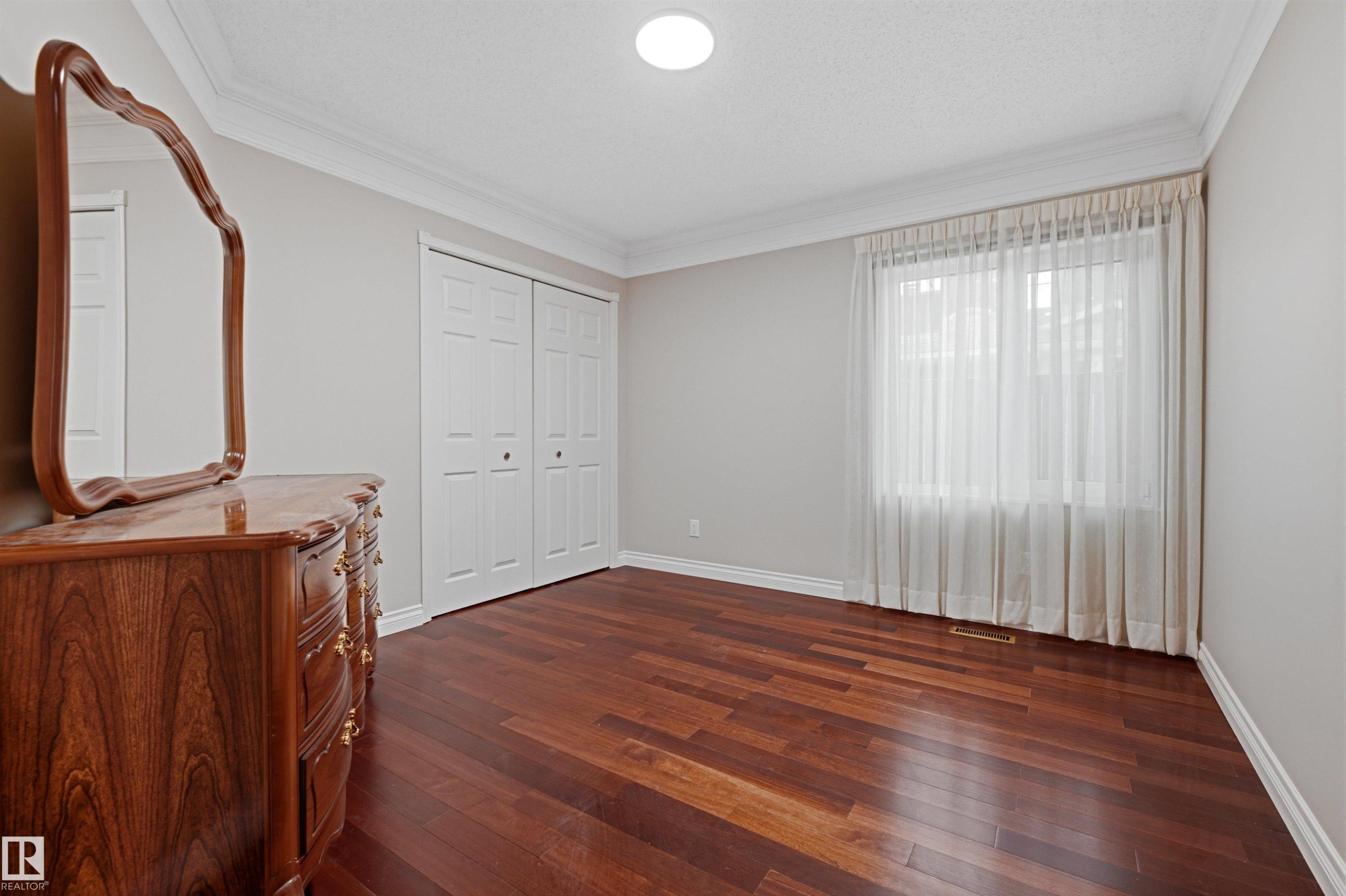 This room features rich hardwood flooring, neutral wall paint, and a window dressed with sheer curtains - 131 Walsh Crescent, Edmonton, AB - Indoor Photo Showing Other Room