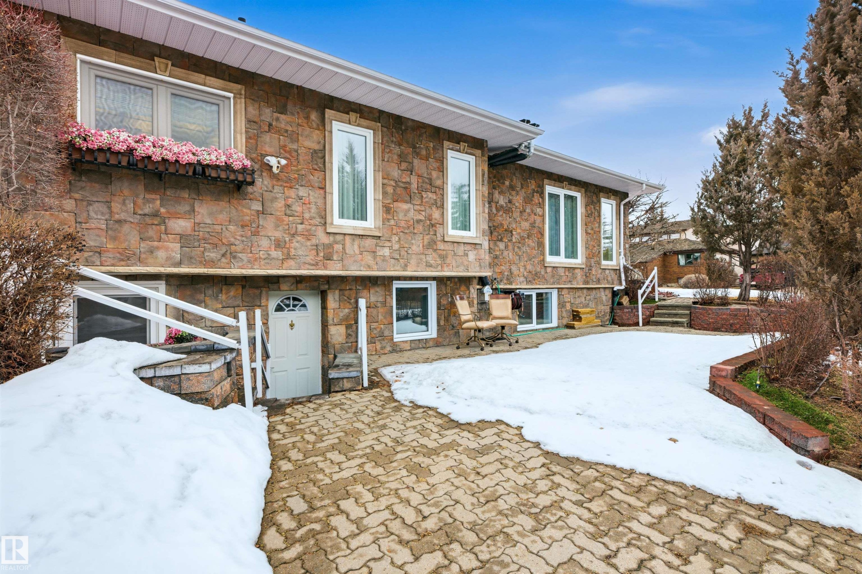 The property features a stone facade with white-framed windows - 131 Walsh Crescent, Edmonton, AB - Outdoor