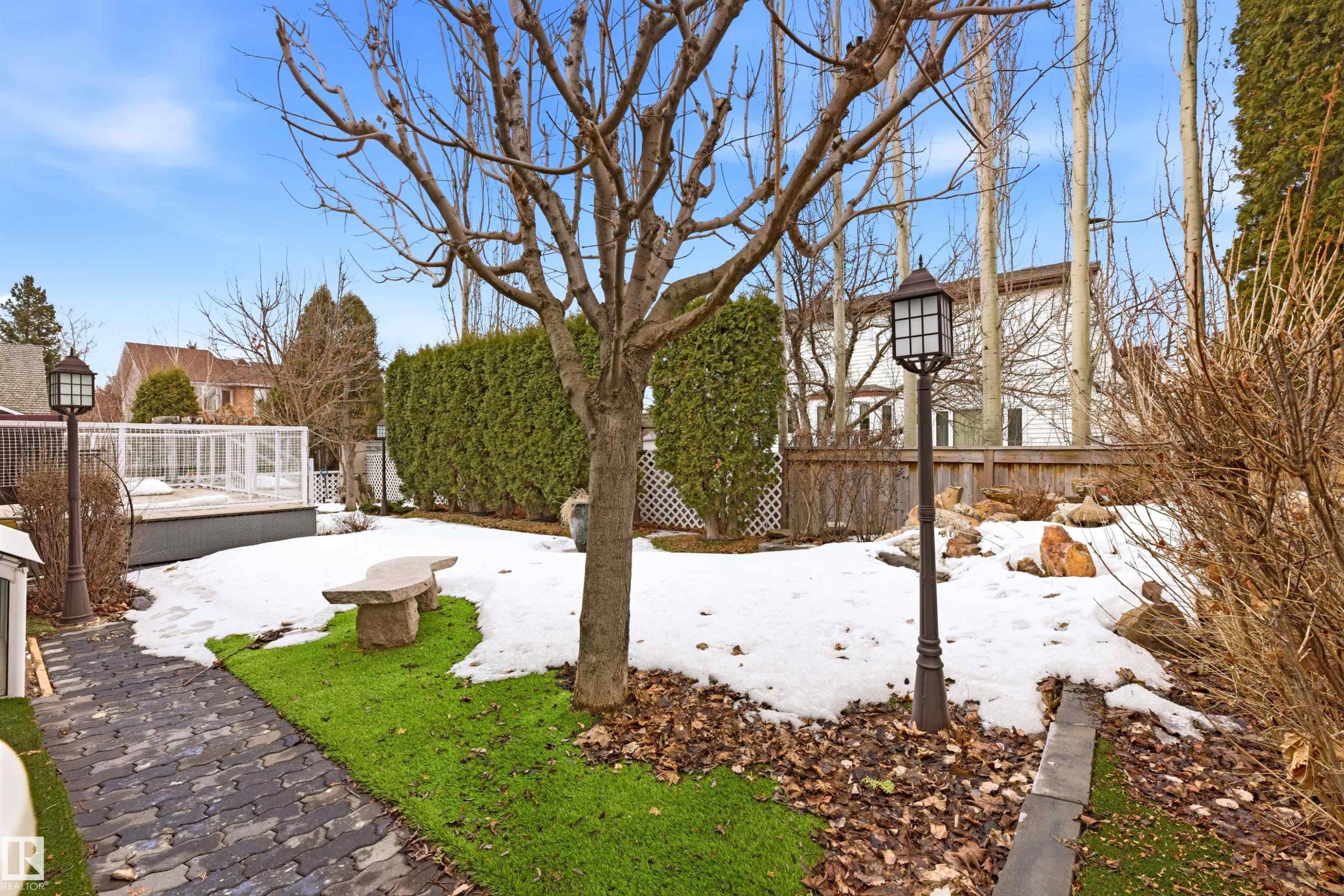 The property features an extensive yard with a paved walkway, a stone bench, and an outdoor light fixture - 131 Walsh Crescent, Edmonton, AB - Outdoor