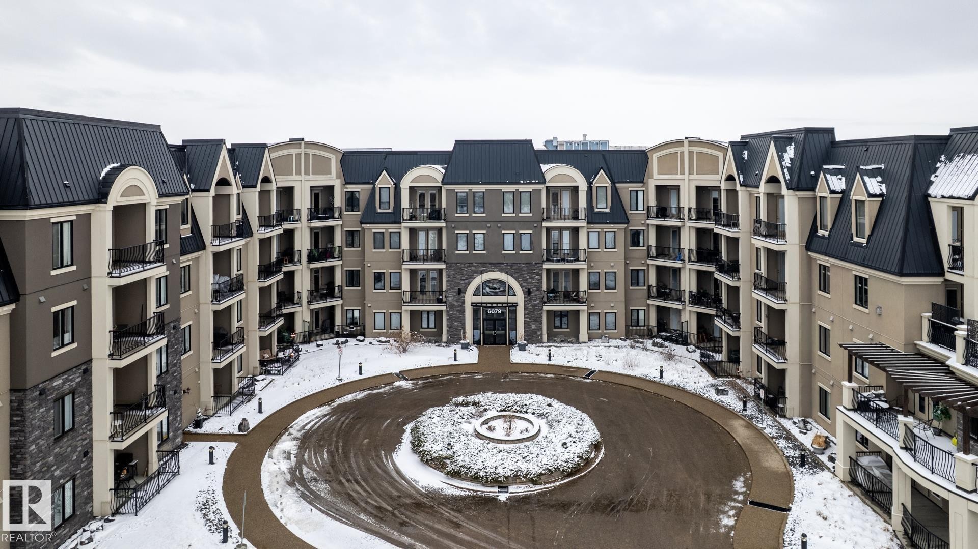 The property features a large circular driveway with a central garden area - 454 6079 Maynard Way, Edmonton, AB - Outdoor With Facade