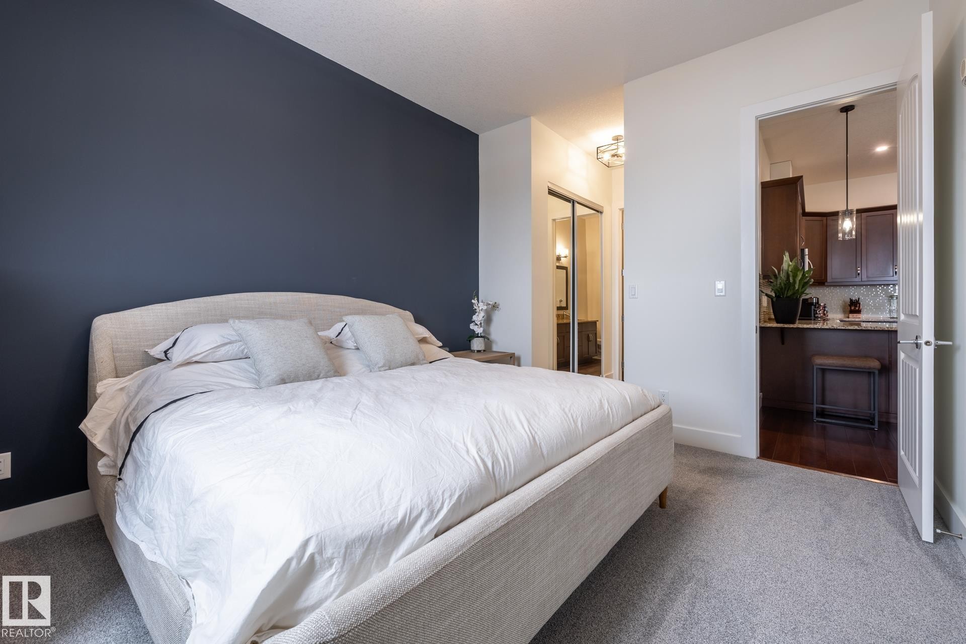 A comfortable room with a neutral-colored bed frame and a dark accent wall - 454 6079 Maynard Way, Edmonton, AB - Indoor Photo Showing Bedroom