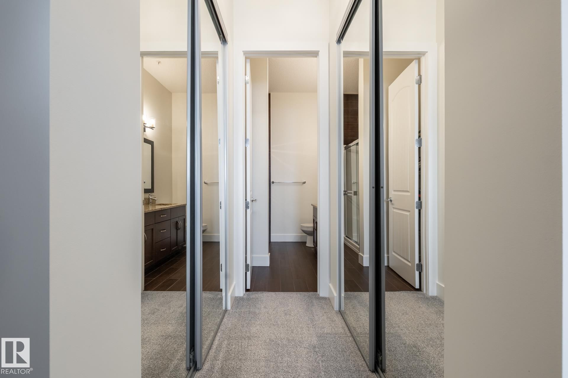 Hallway to ensuite featuring mirrored sliding closet doors and light-colored carpeting - 454 6079 Maynard Way, Edmonton, AB - Indoor Photo Showing Other Room