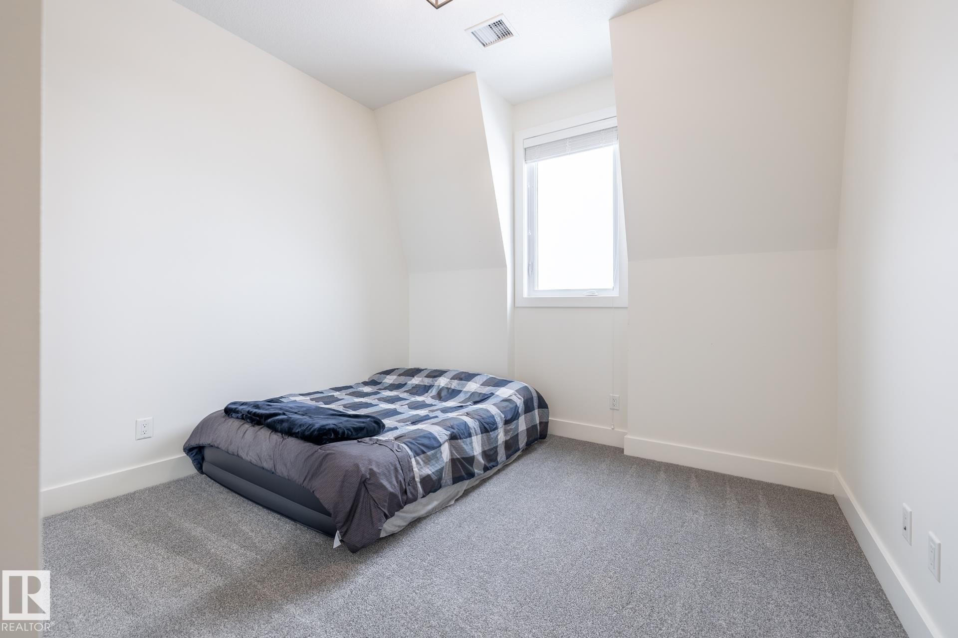 The room features light gray carpeting, white walls, and a window providing natural light - 454 6079 Maynard Way, Edmonton, AB - Indoor Photo Showing Bedroom