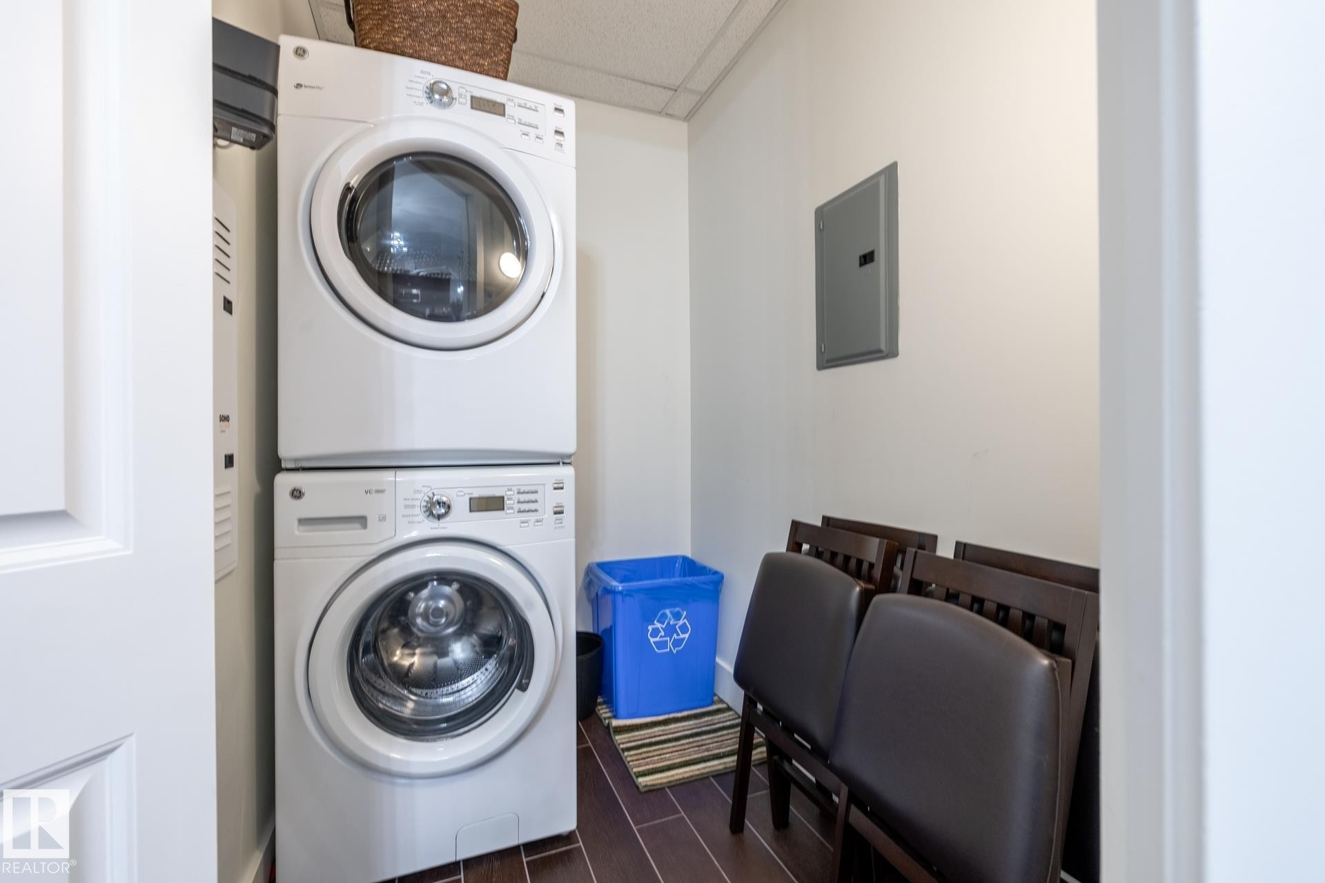 Laundry area featuring a stackable washer and dryer, and dark tile flooring - 454 6079 Maynard Way, Edmonton, AB - Indoor Photo Showing Laundry Room