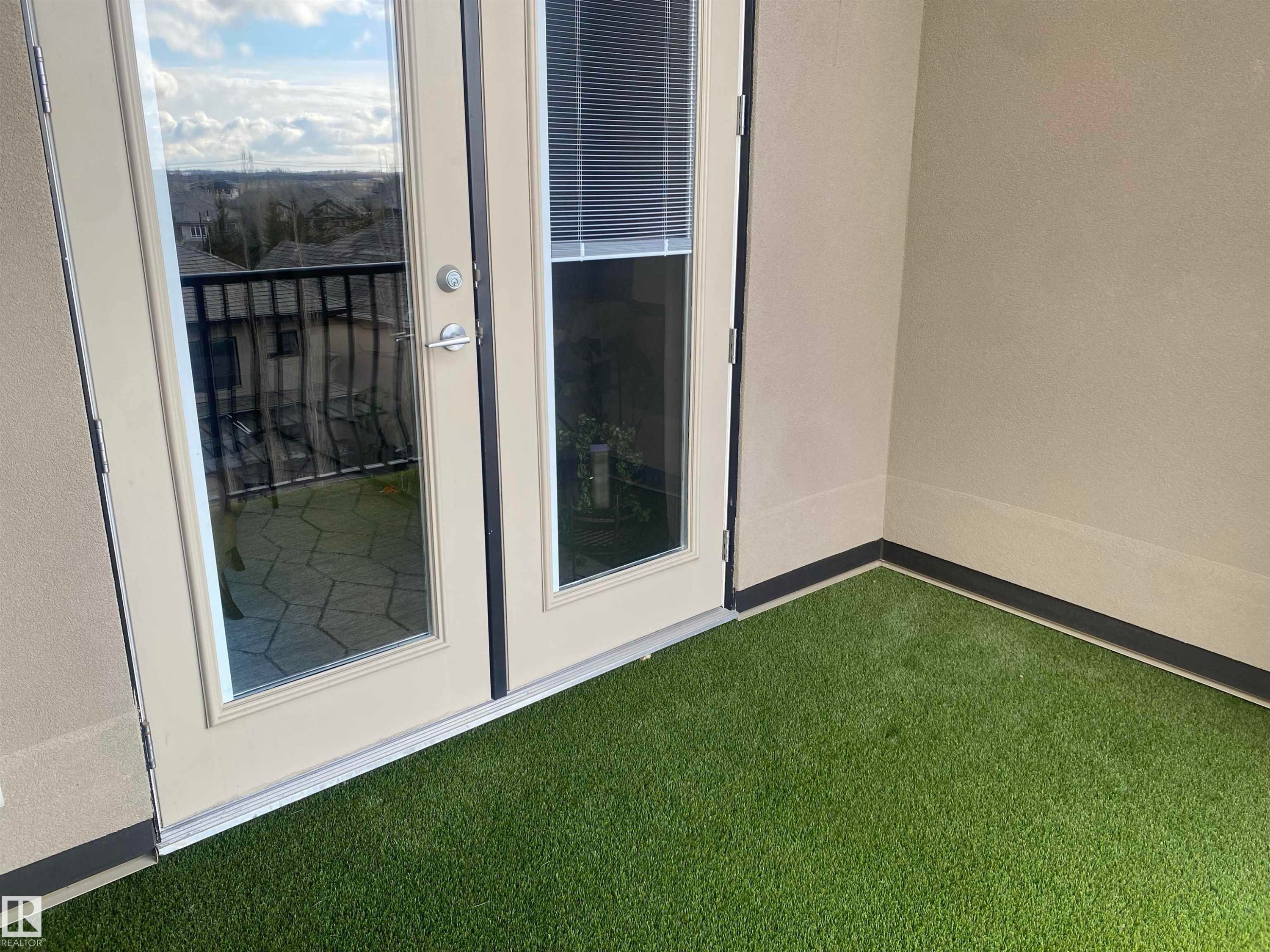 The property features a balcony with artificial turf flooring and a partial view of the surrounding neighborhood - 454 6079 Maynard Way, Edmonton, AB - Photo Showing Other Room