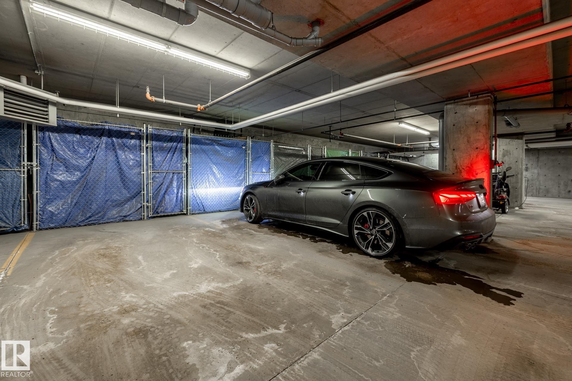 Underground parking space with concrete flooring and overhead lighting - 454 6079 Maynard Way, Edmonton, AB - Indoor Photo Showing Garage