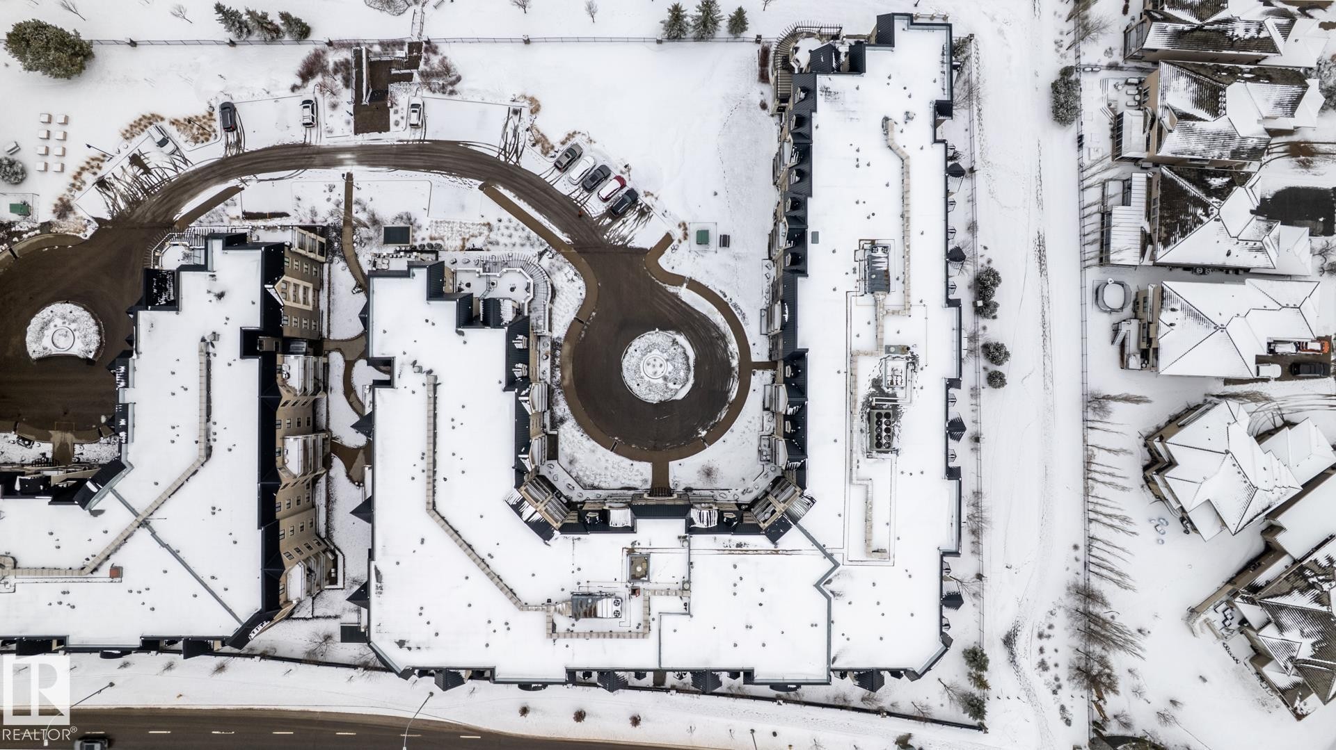 Aerial view of the property and surrounding neighborhood, featuring a large circular drive and parking areas - 454 6079 Maynard Way, Edmonton, AB -
