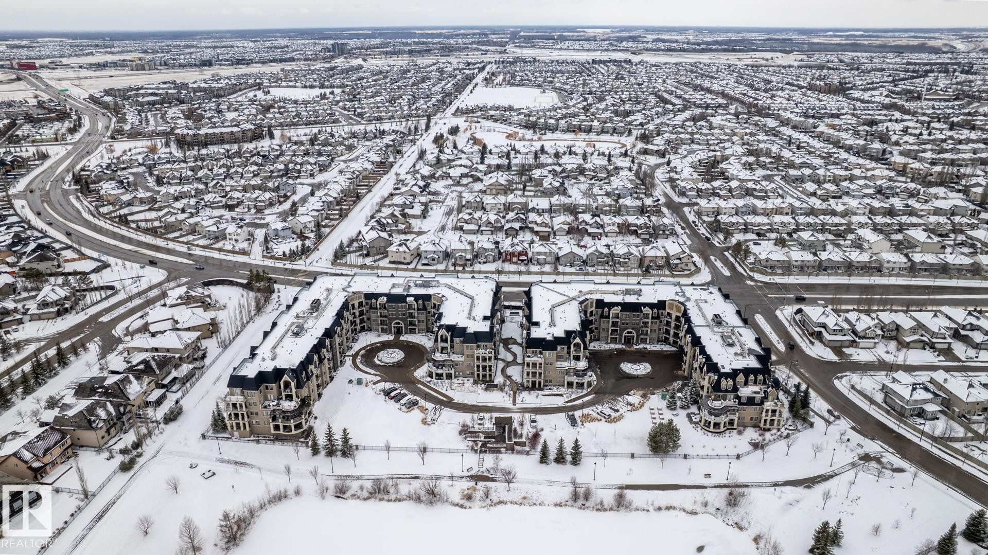 Aerial view showcasing the property's distinct architectural style, surrounded by a residential neighborhood with snow-covered rooftops - 454 6079 Maynard Way, Edmonton, AB - Outdoor With View