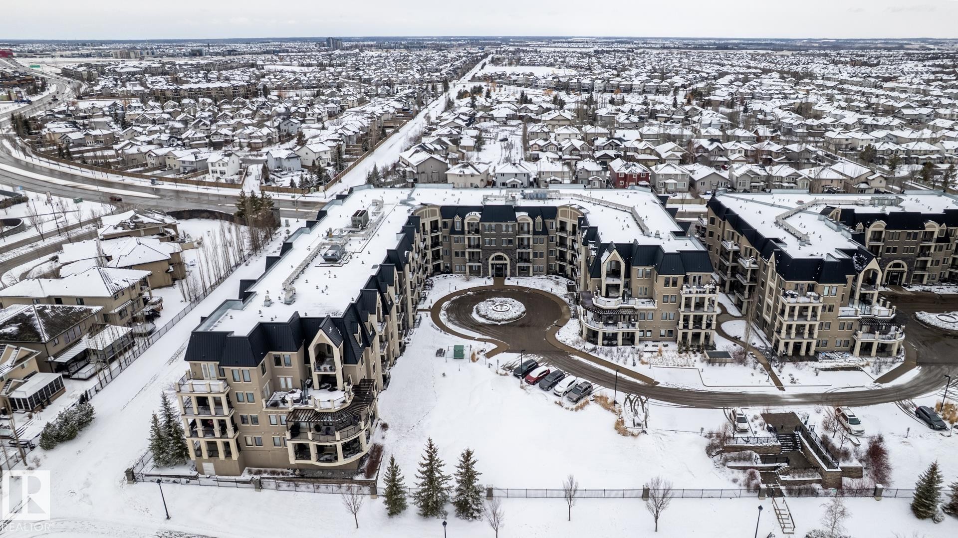 Aerial view of the property, showcasing its distinctive architectural style with dark sloped roofs and light-colored facades - 454 6079 Maynard Way, Edmonton, AB - Outdoor With View