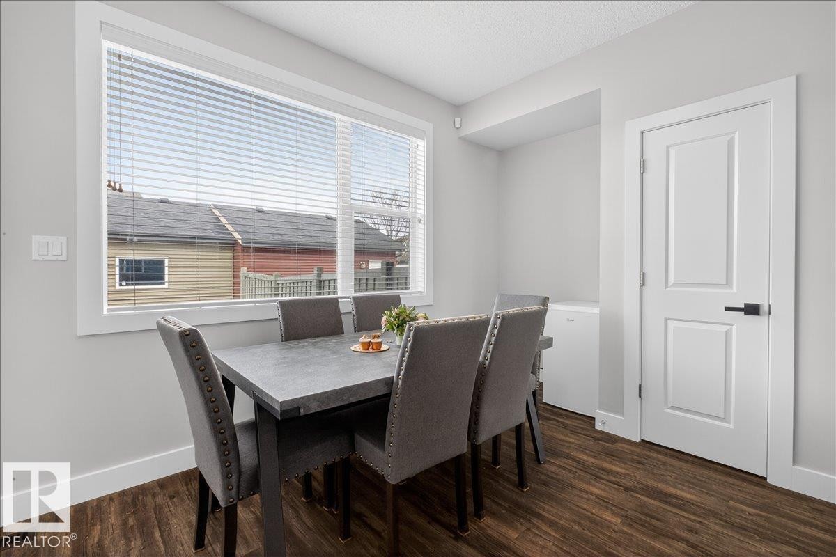 Dining area featuring wood-look flooring, light grey walls, and a window with horizontal blinds - 9034 Rosenthal Link, Edmonton, AB - Indoor Photo Showing Dining Room
