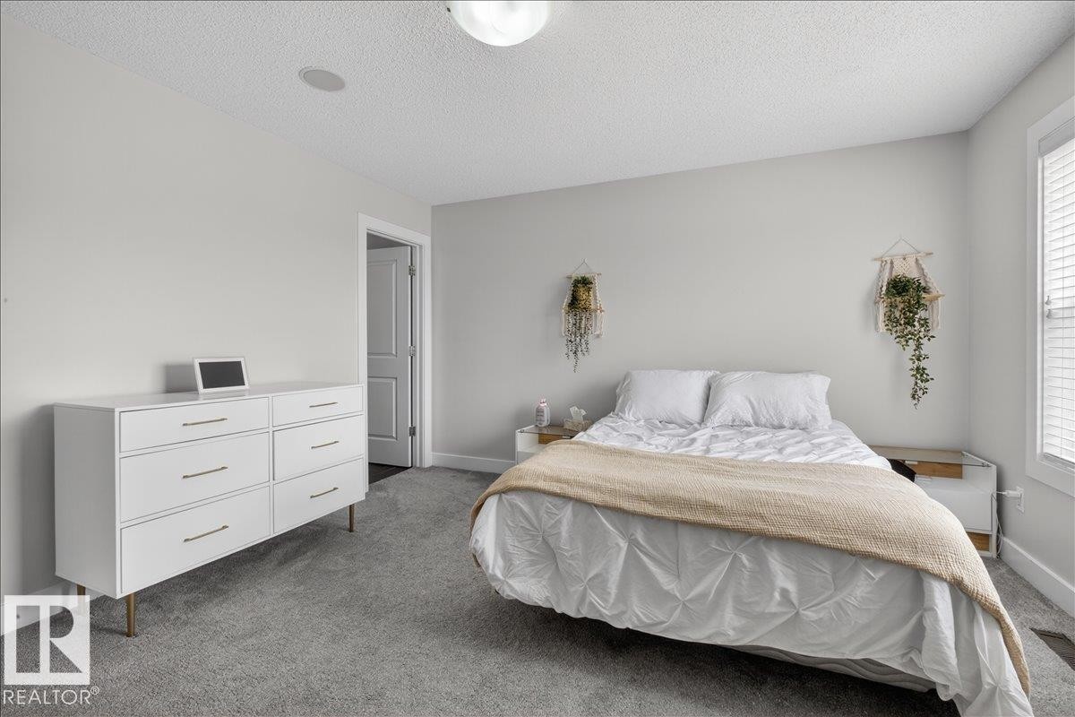 This room features light gray walls, gray carpeting, and a window with white blinds - 9034 Rosenthal Link, Edmonton, AB - Indoor Photo Showing Bedroom