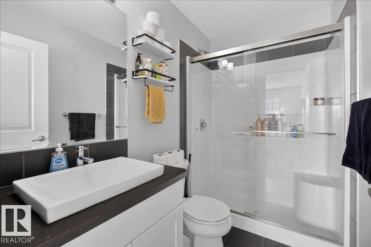 The bathroom features a contemporary vanity with a rectangular vessel sink and a wall-mounted mirror - 9034 Rosenthal Link, Edmonton, AB - Indoor Photo Showing Bathroom