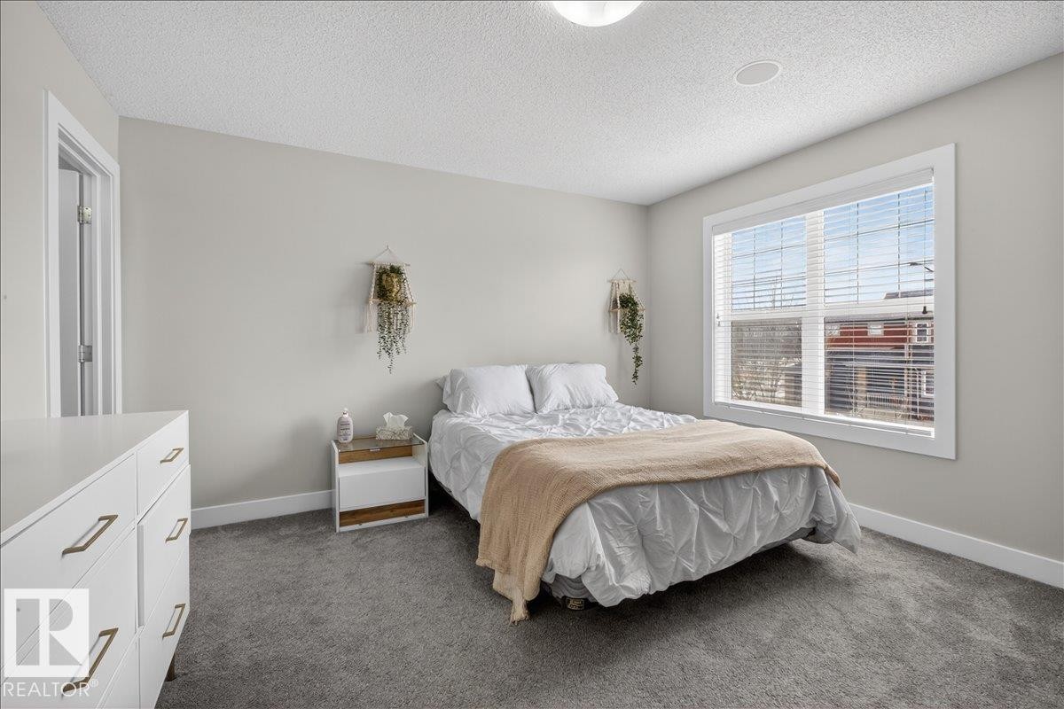 This room features light grey walls and grey carpeting, creating a neutral aesthetic - 9034 Rosenthal Link, Edmonton, AB - Indoor Photo Showing Bedroom