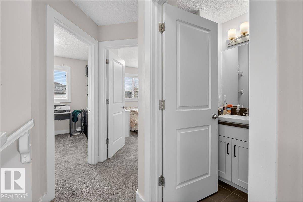 View of a hallway featuring neutral-toned walls, white trim, and a textured ceiling - 9034 Rosenthal Link, Edmonton, AB - Indoor Photo Showing Other Room